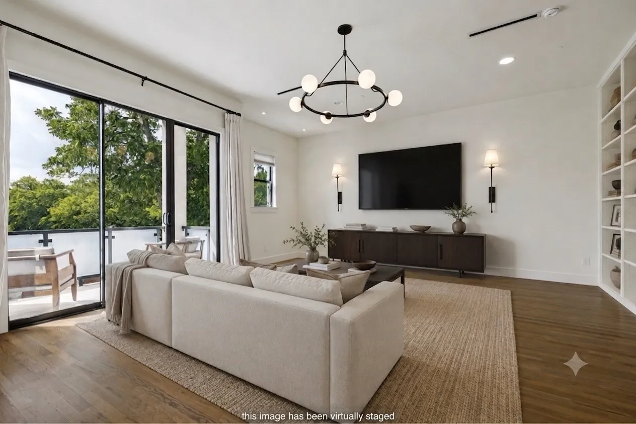 Spacious living area featuring hard surface flooring, built-in shelving, and a large sliding glass door opening to an outdoor balcony