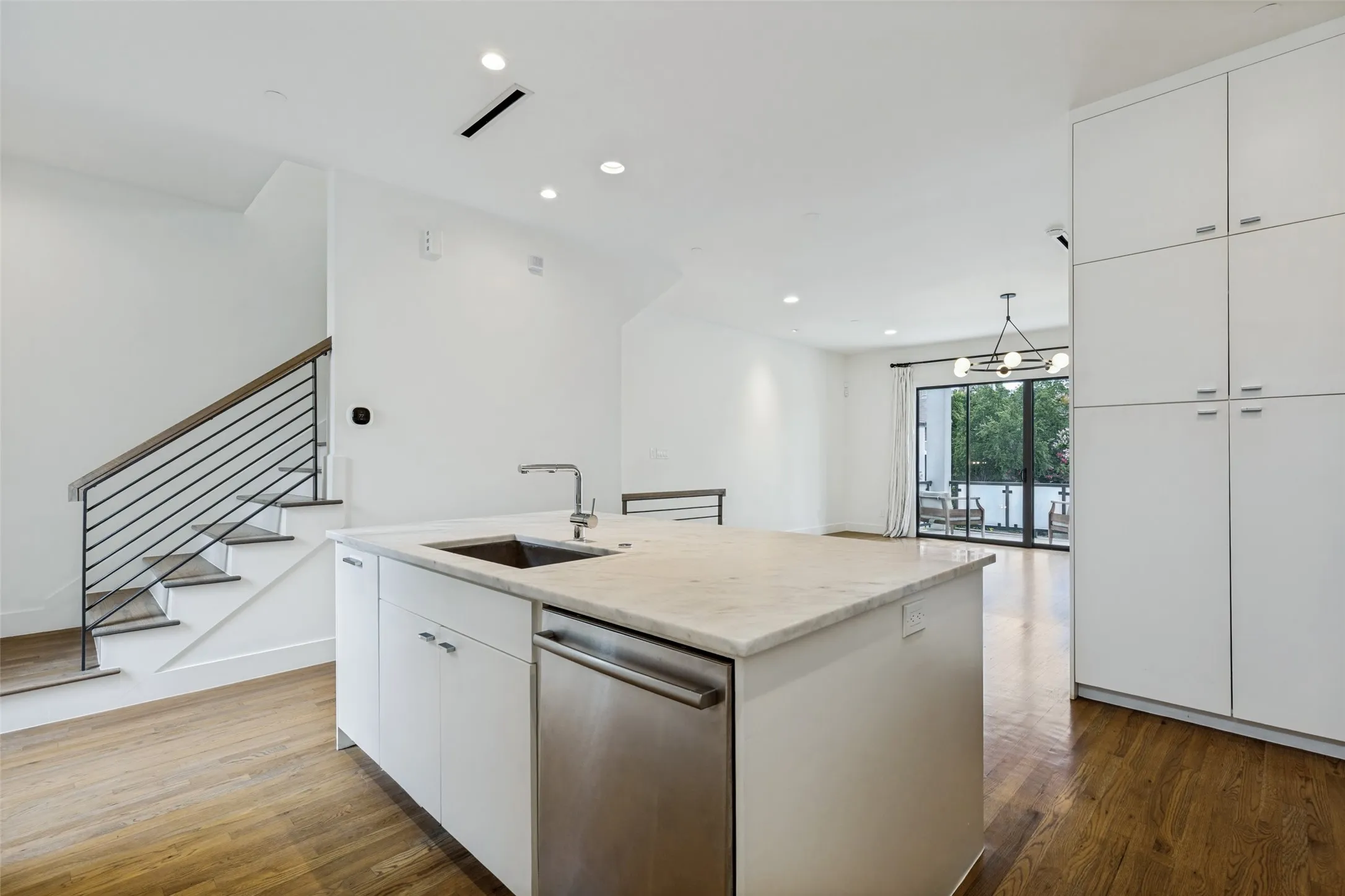 Spacious kitchen featuring a large central island with an undermount sink and stainless steel dishwasher