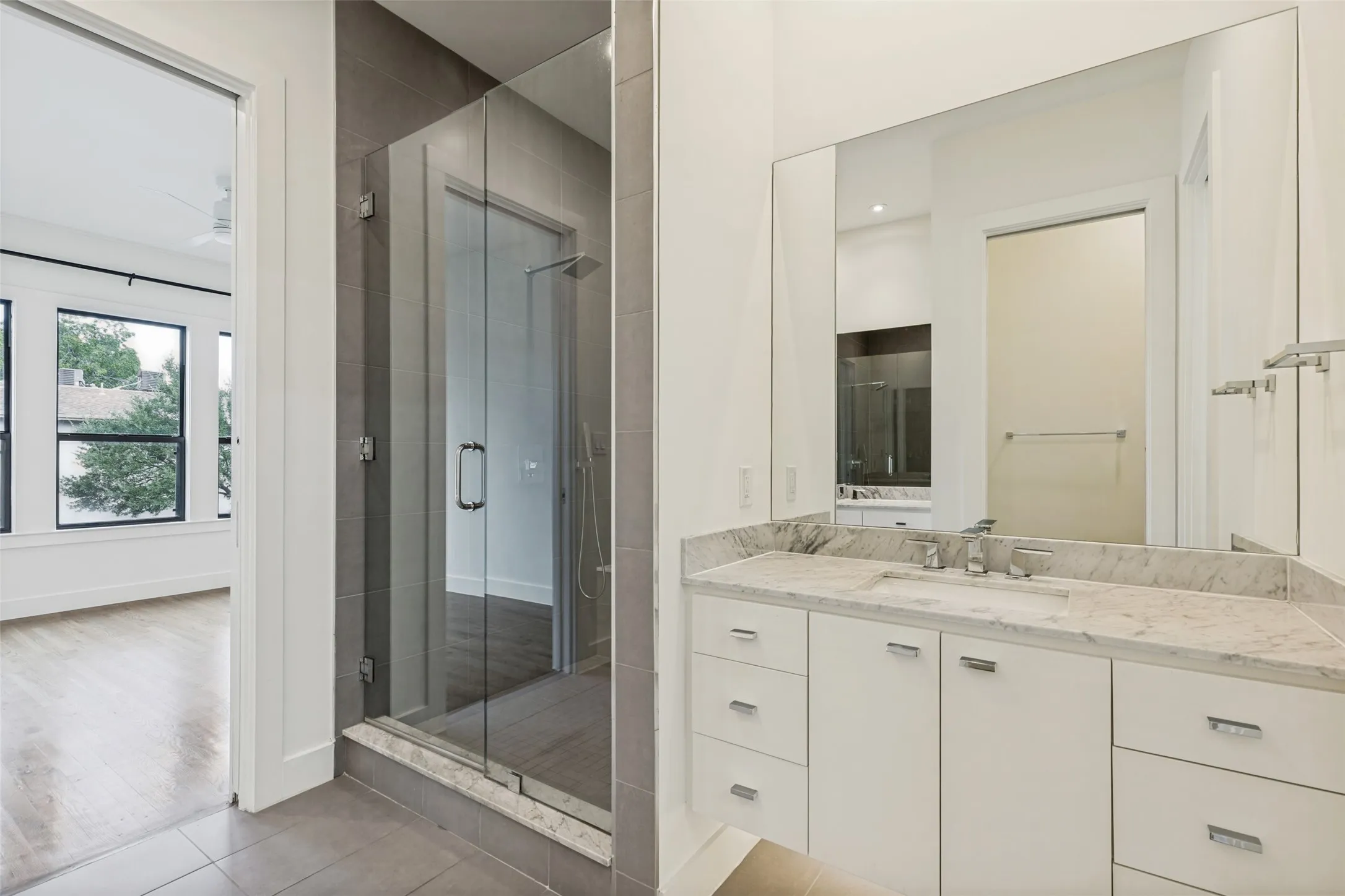 Bathroom featuring a spacious vanity with a light-colored stone countertop, dual undermount sinks, and white cabinetry