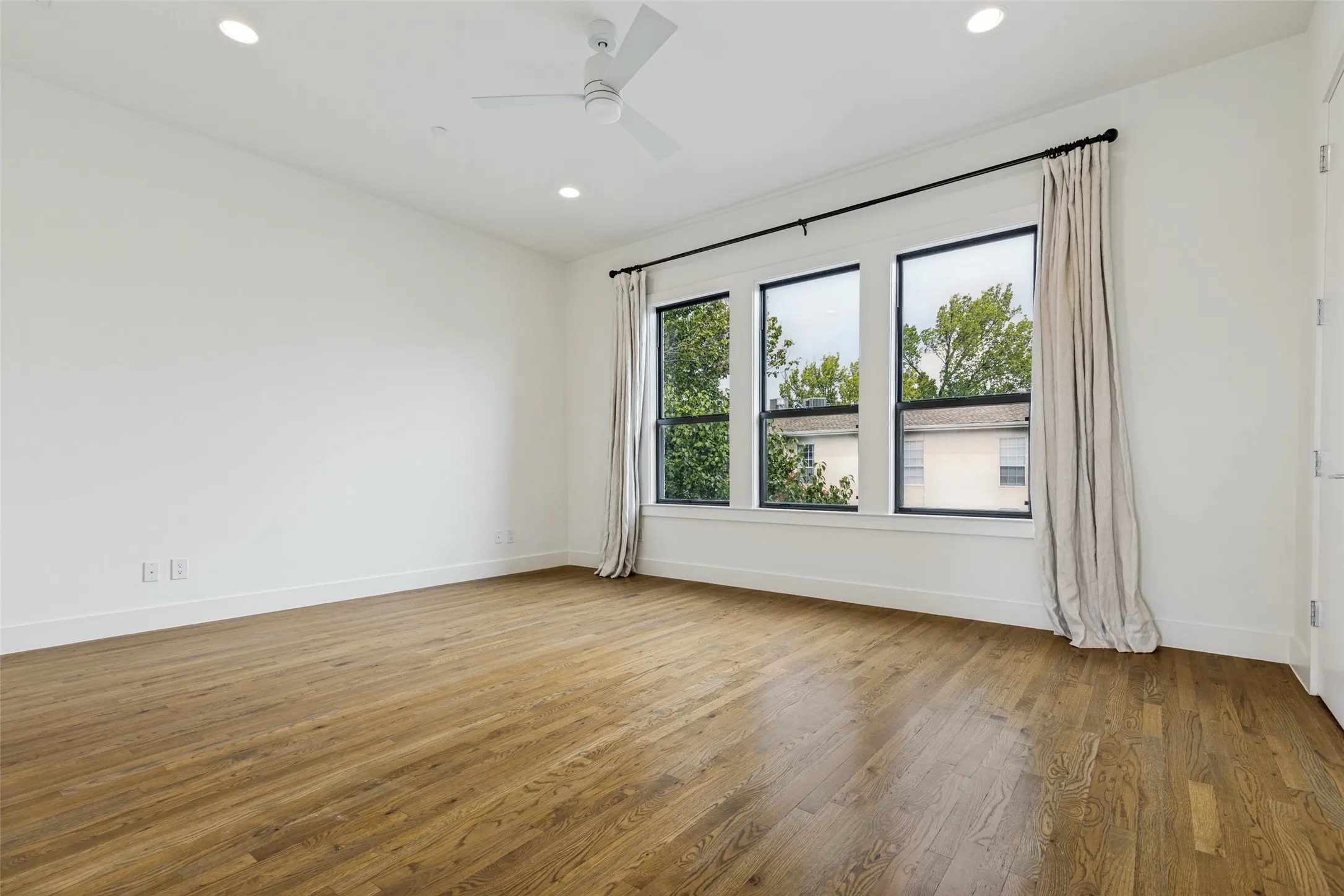 Spacious room featuring wood-finish flooring and a white ceiling fan