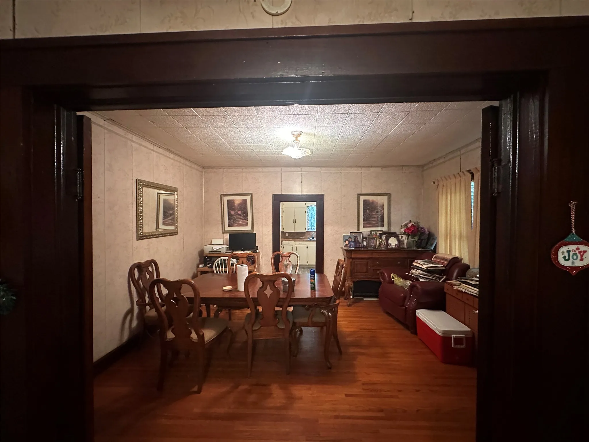 Dining area featuring wood-finish flooring, a decorative ceiling, and a doorway to an additional room