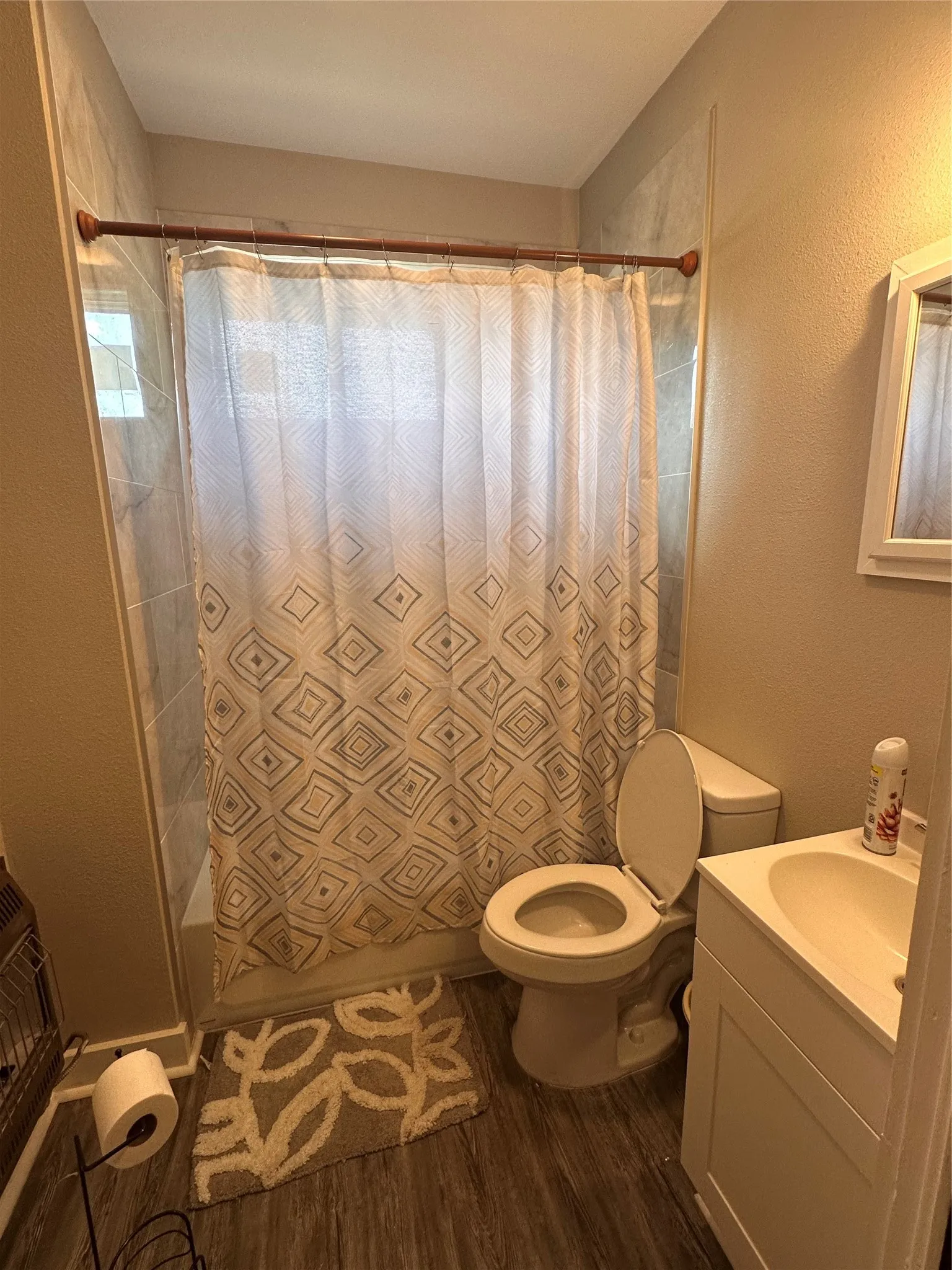 Bathroom featuring a shower/tub combination with tile surround, a single vanity with an integrated sink, and wood-finish flooring