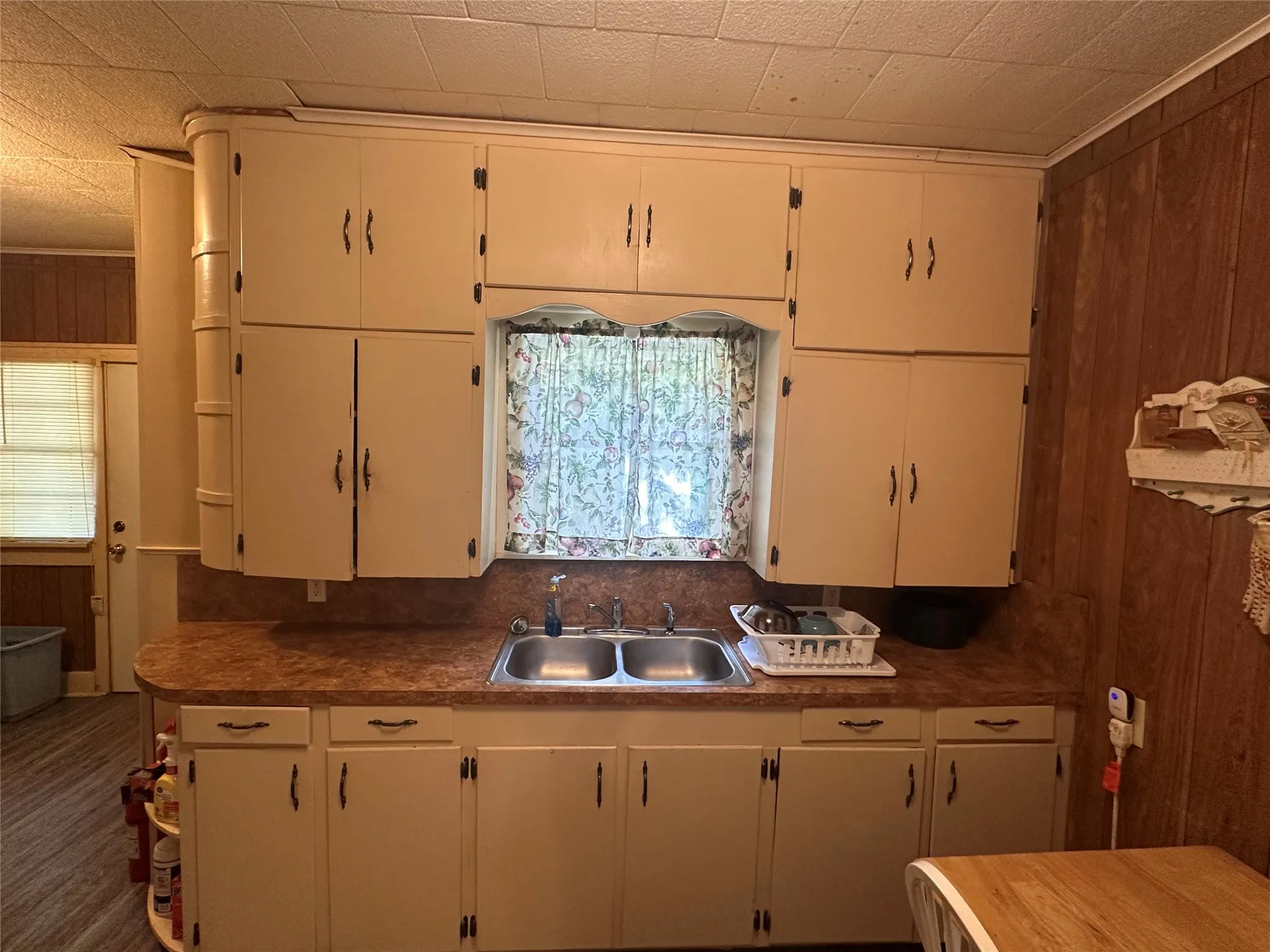 Kitchen featuring abundant cabinetry, a double basin stainless steel sink, and wood-finish wall paneling