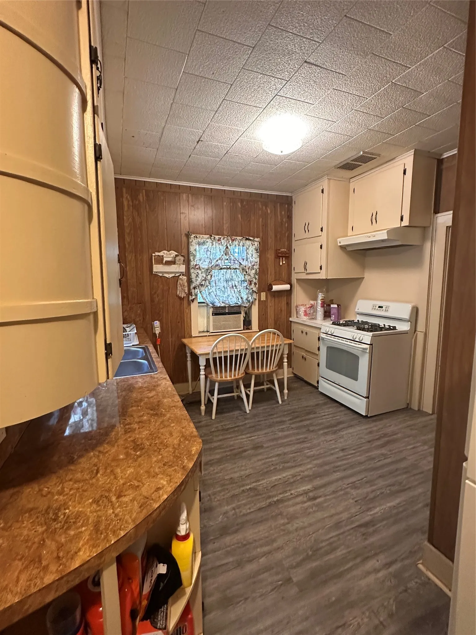 Kitchen featuring wood paneling, wood-finish flooring, and cream-colored cabinetry
