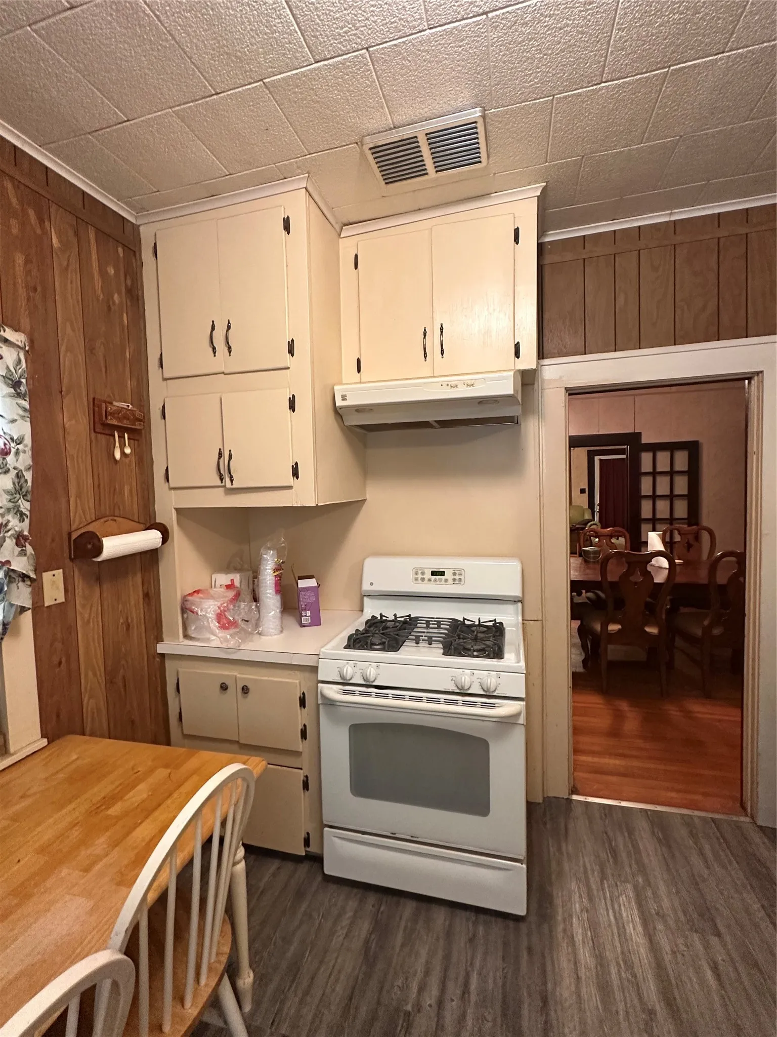 Kitchen featuring wood-panel accent walls, light-toned cabinetry, and wood-finish flooring