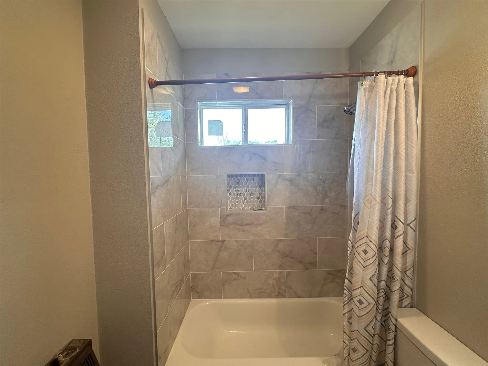 Built-in bathtub with subway tile surround featuring a decorative tile niche