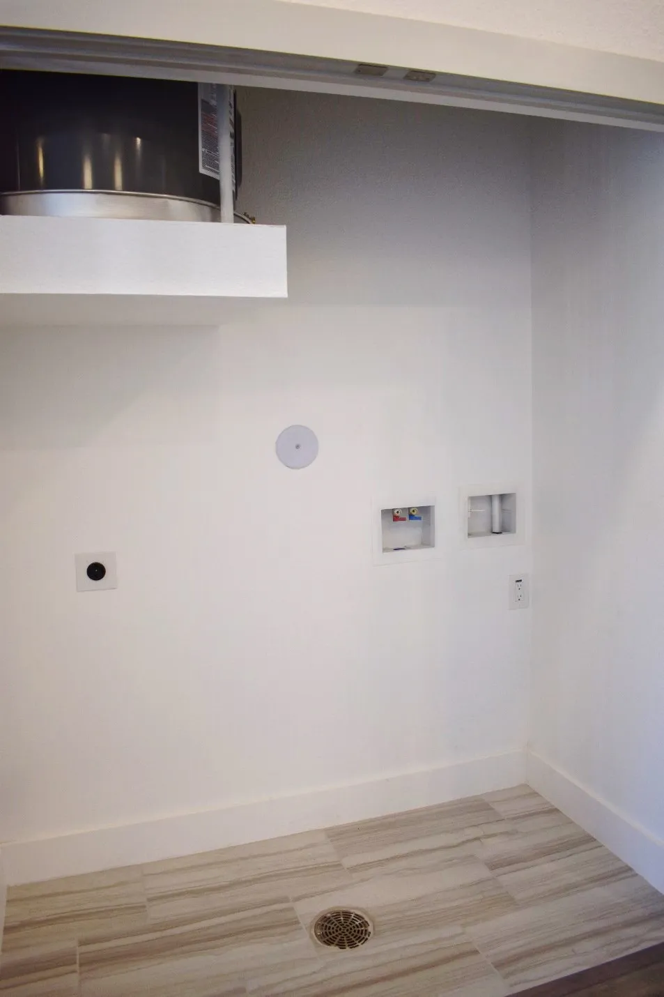 Dedicated utility space featuring tile flooring with a central drain