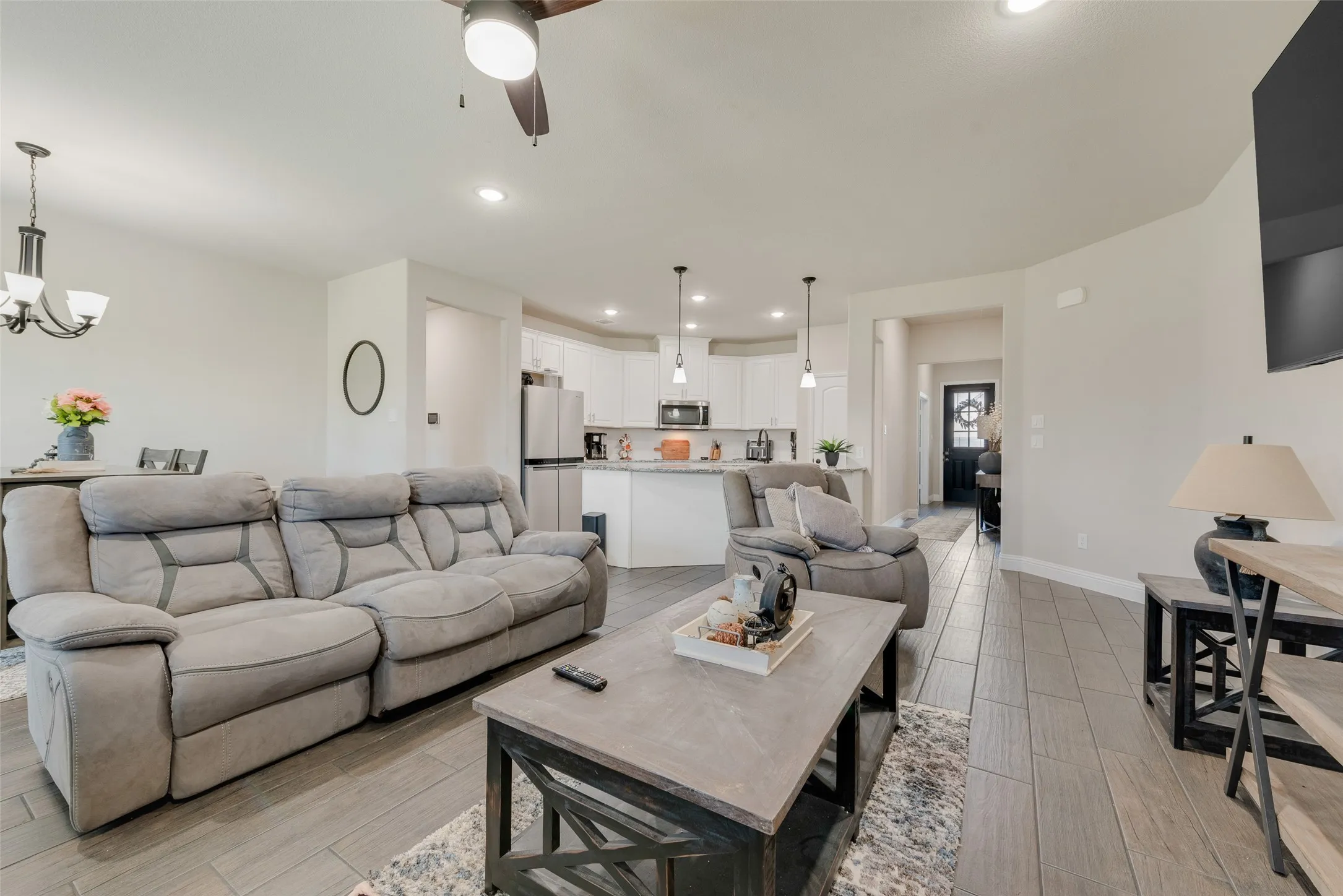 Living room featuring light wood finished floors, ceiling fan, a chandelier, and recessed lighting