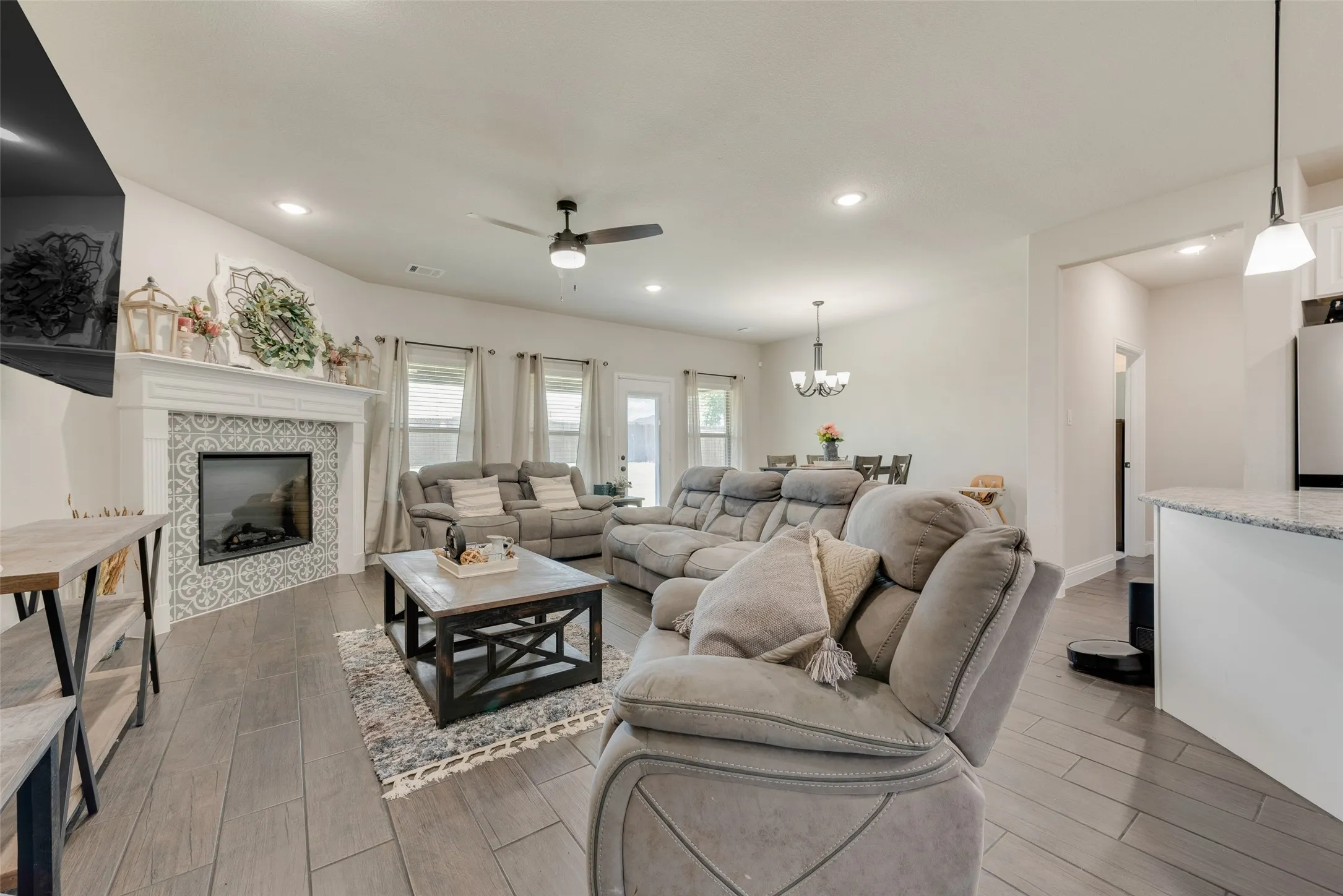 Living area featuring ceiling fan, wood finished floors, a fireplace, a chandelier, and recessed lighting