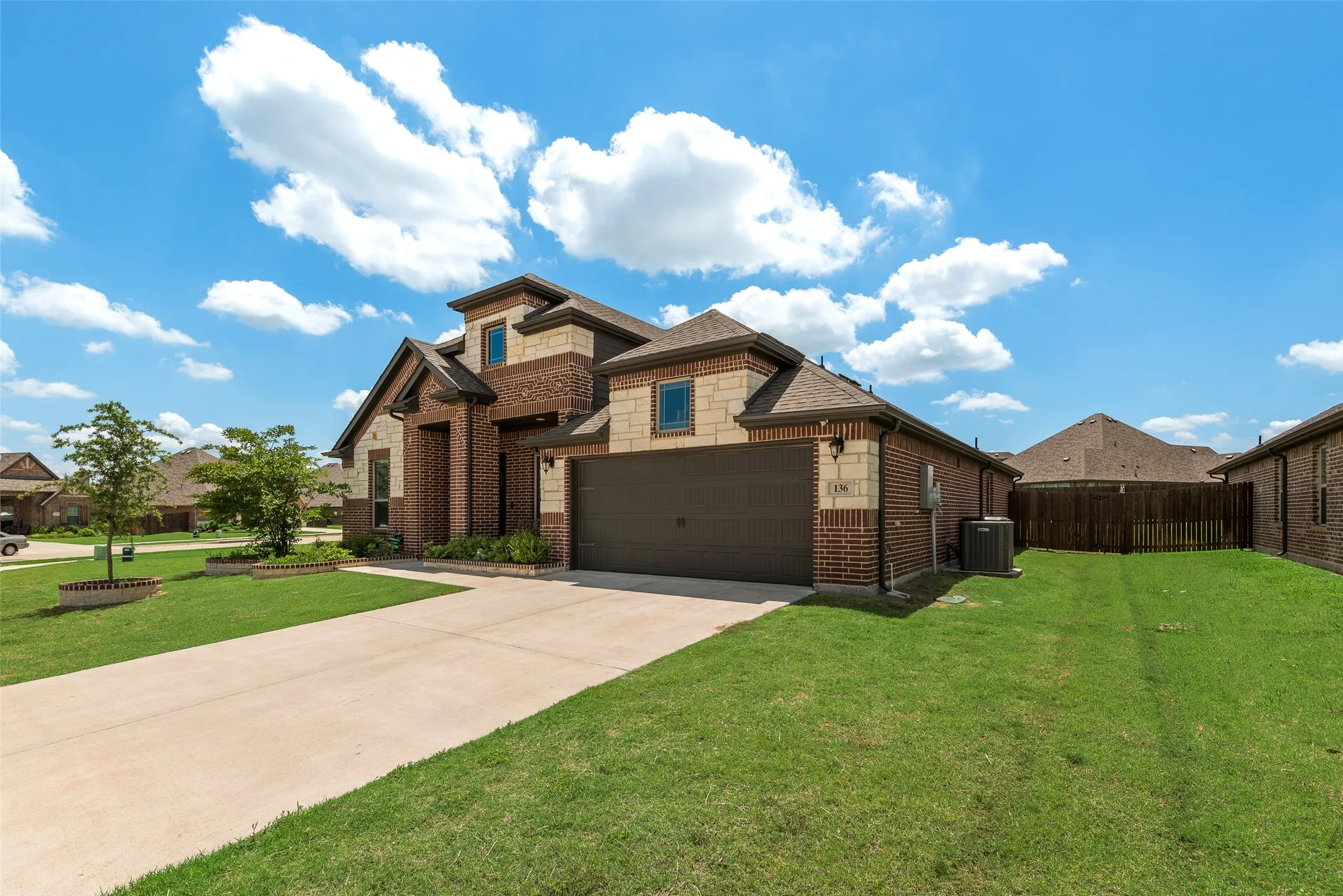 View of front of home featuring stone siding, concrete driveway, and brick siding