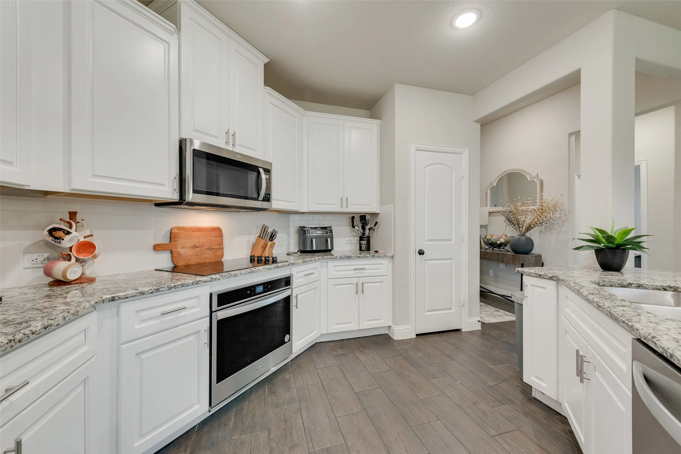 Kitchen featuring stainless steel appliances, white cabinetry, tasteful backsplash, dark wood finished floors, and recessed lighting