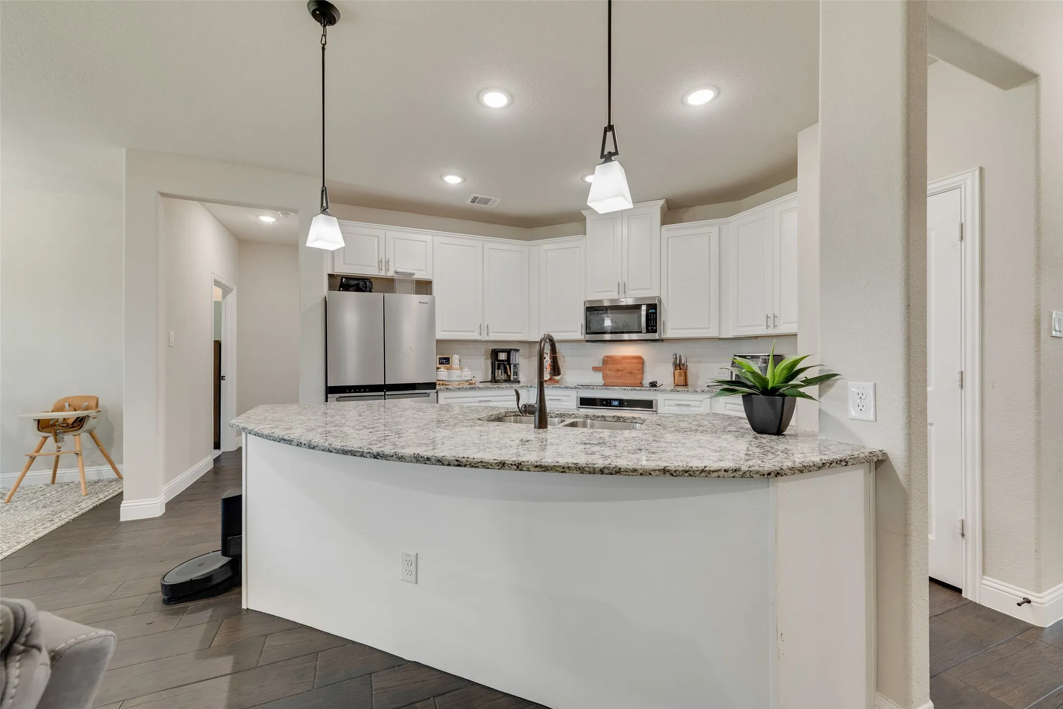 Kitchen featuring stainless steel appliances, white cabinets, dark wood-style flooring, light stone counters, and recessed lighting