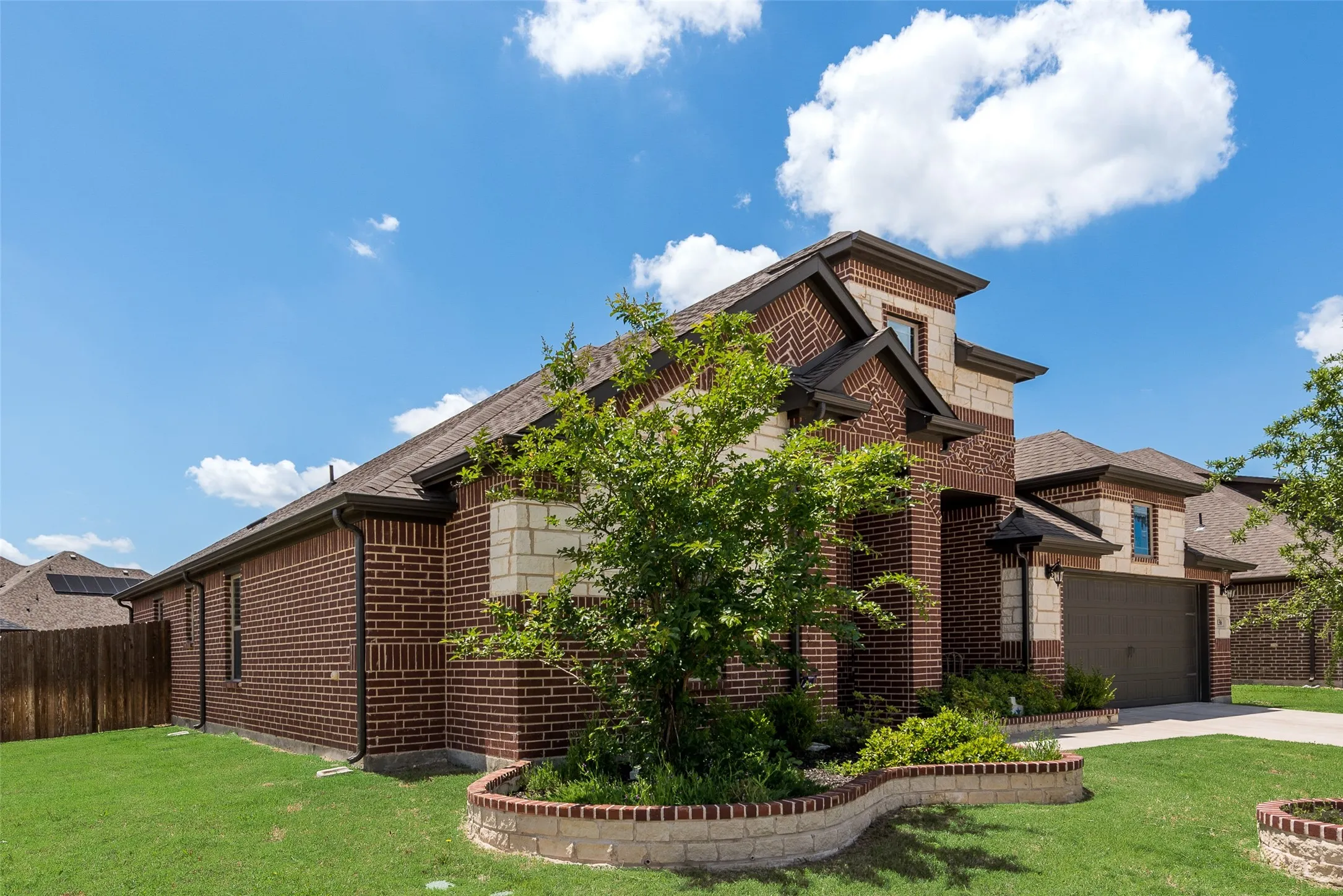 View of side of home with brick siding, driveway, and roof with shingles