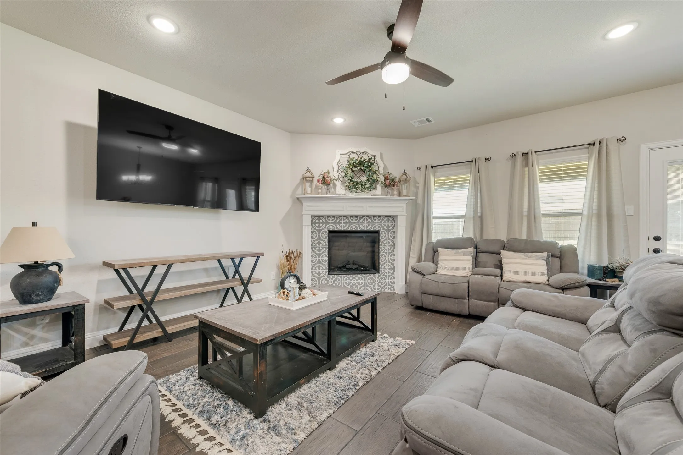 Living room featuring ceiling fan, wood finished floors, a tiled fireplace, and recessed lighting