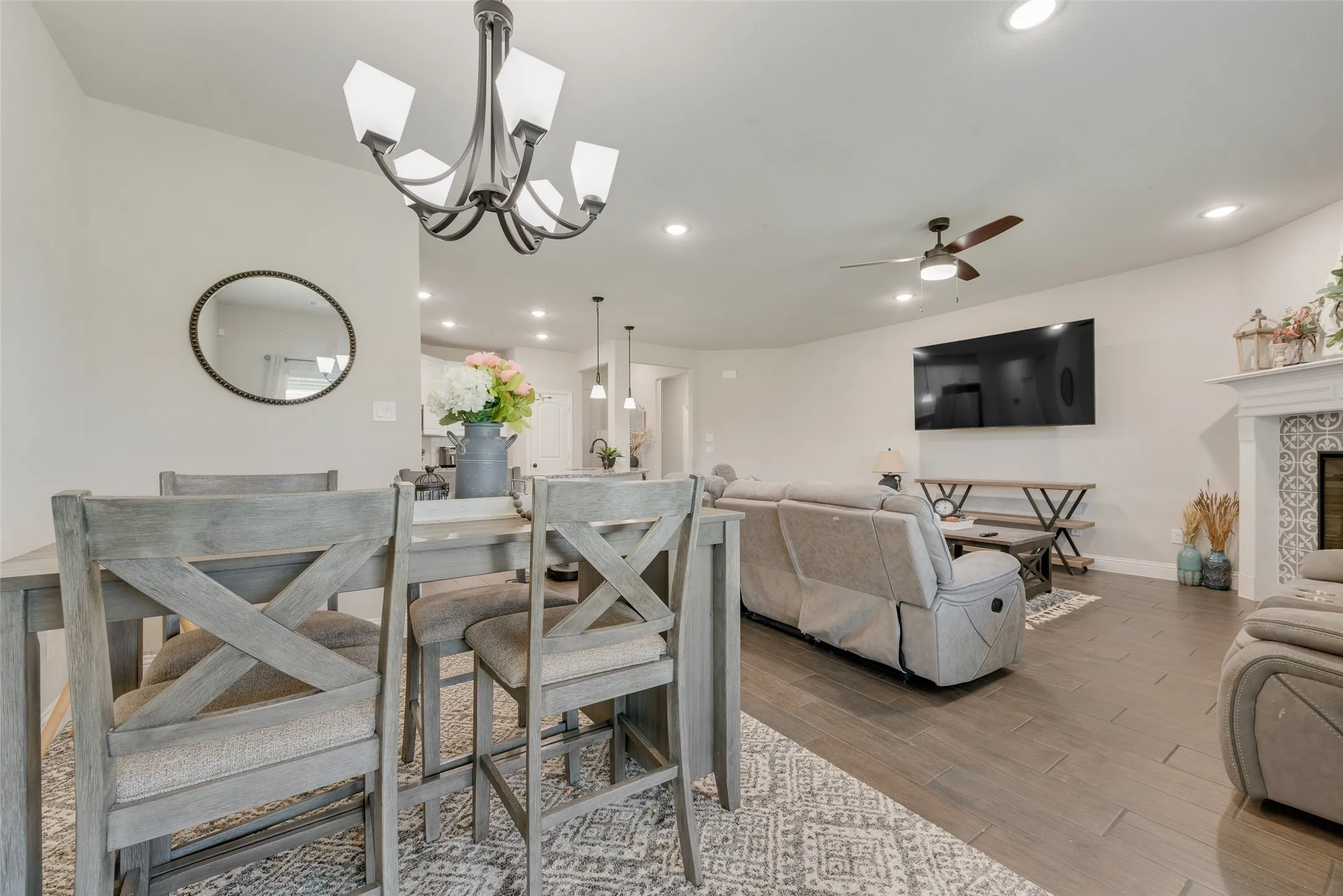 Dining room with wood finished floors, a ceiling fan, recessed lighting, and a tiled fireplace