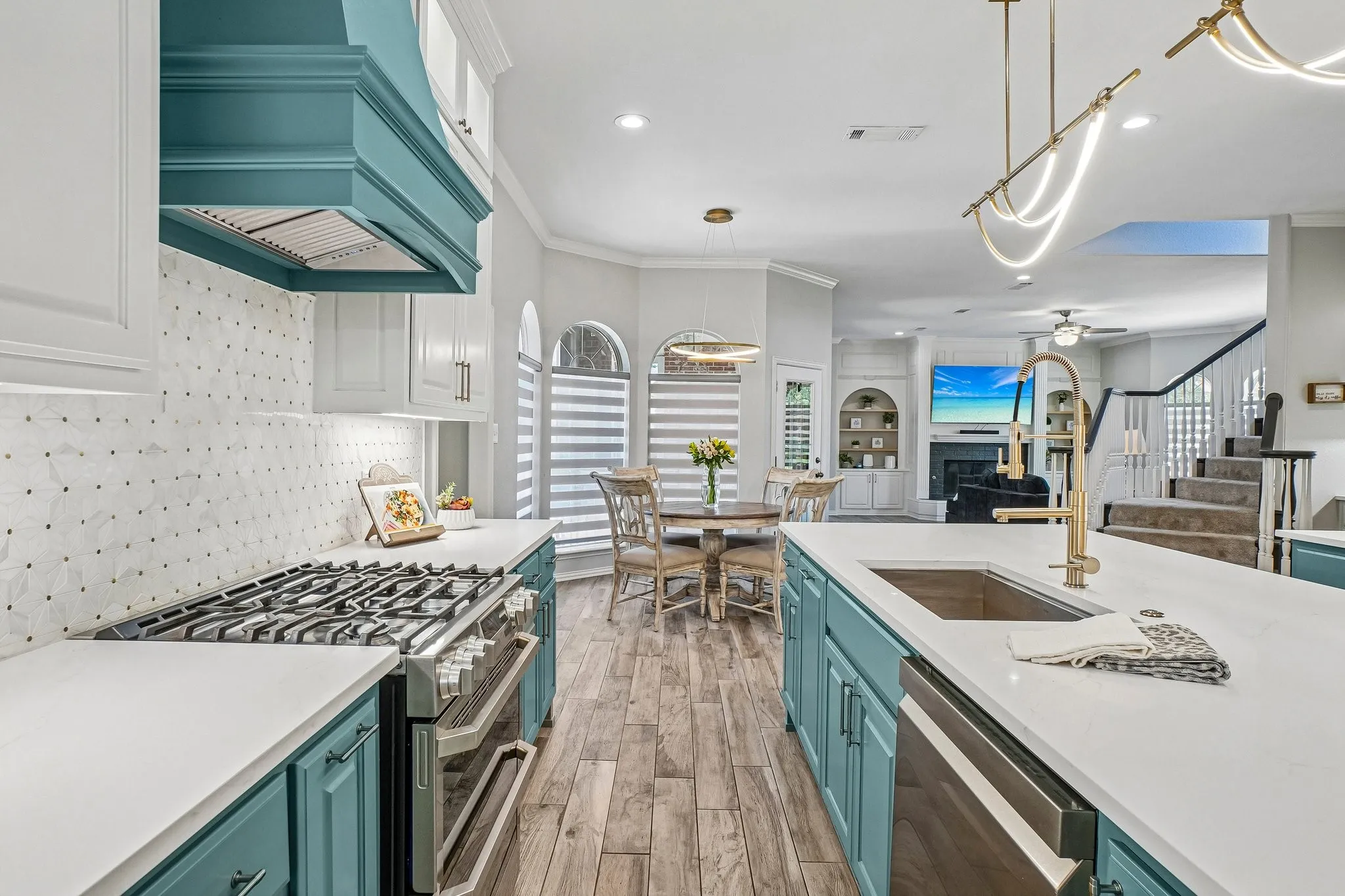 Gourmet kitchen with views of the breakfast area and family room.   Gas range with double ovens,  quartz countertops, and a modern gold-finish faucet