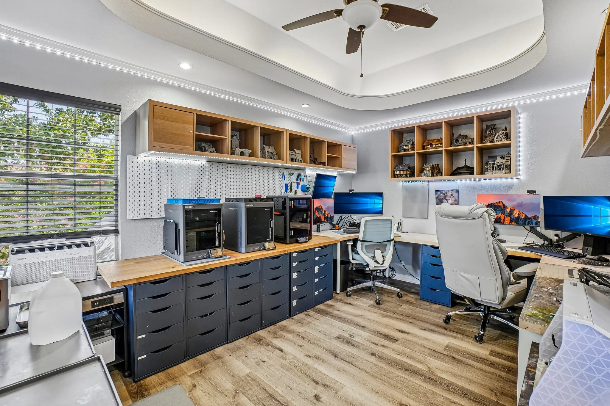 Customizable workspace featuring a tray ceiling with integrated lighting, and multiple built-in shelving units