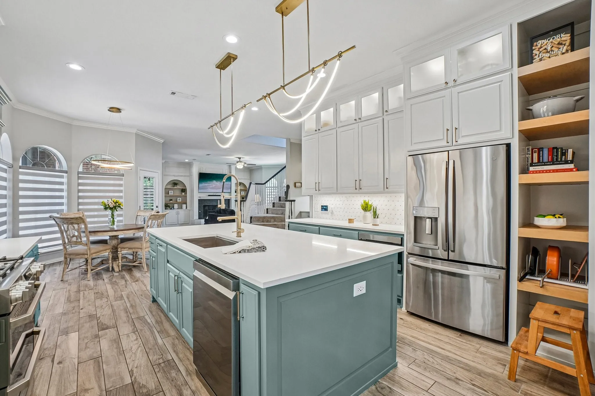 Spacious kitchen featuring a central island with a built-in undermount sink and dishwasher.  Designer lighting and  white quartz countertops add elegance to the space.