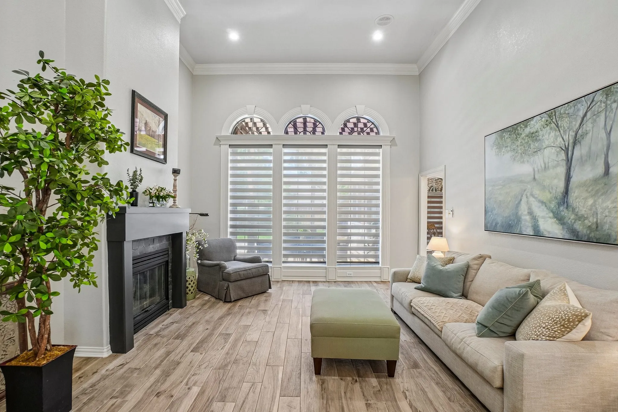 Living area featuring high ceilings with crown molding, a fireplace with a dark mantel, and tall windows with arched transoms