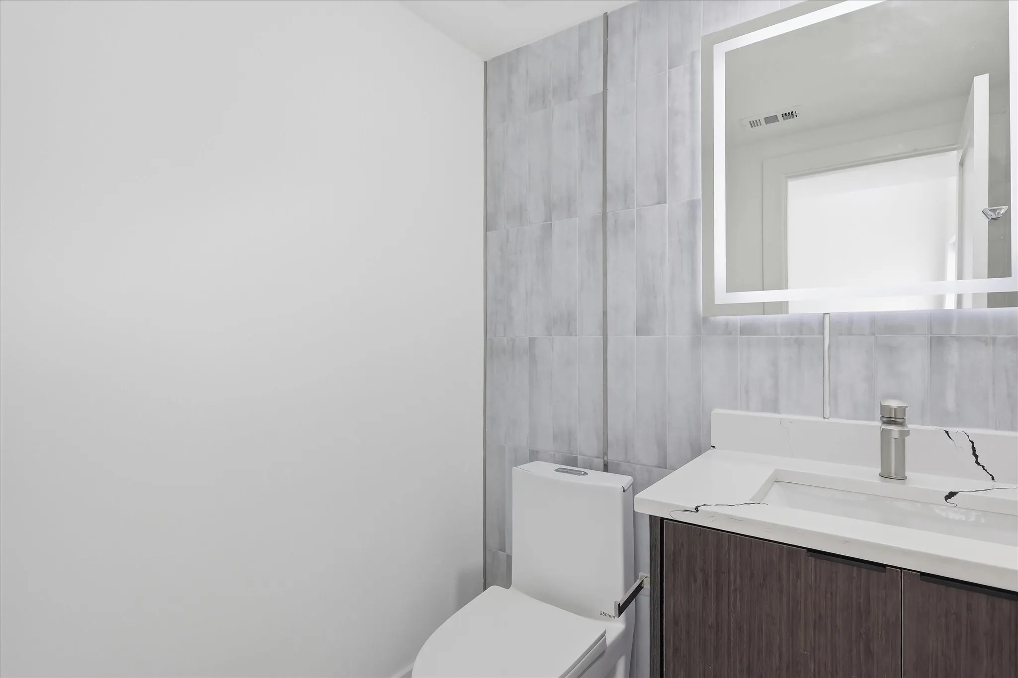Vanity with a white countertop featuring a single basin sink and a brushed nickel faucet