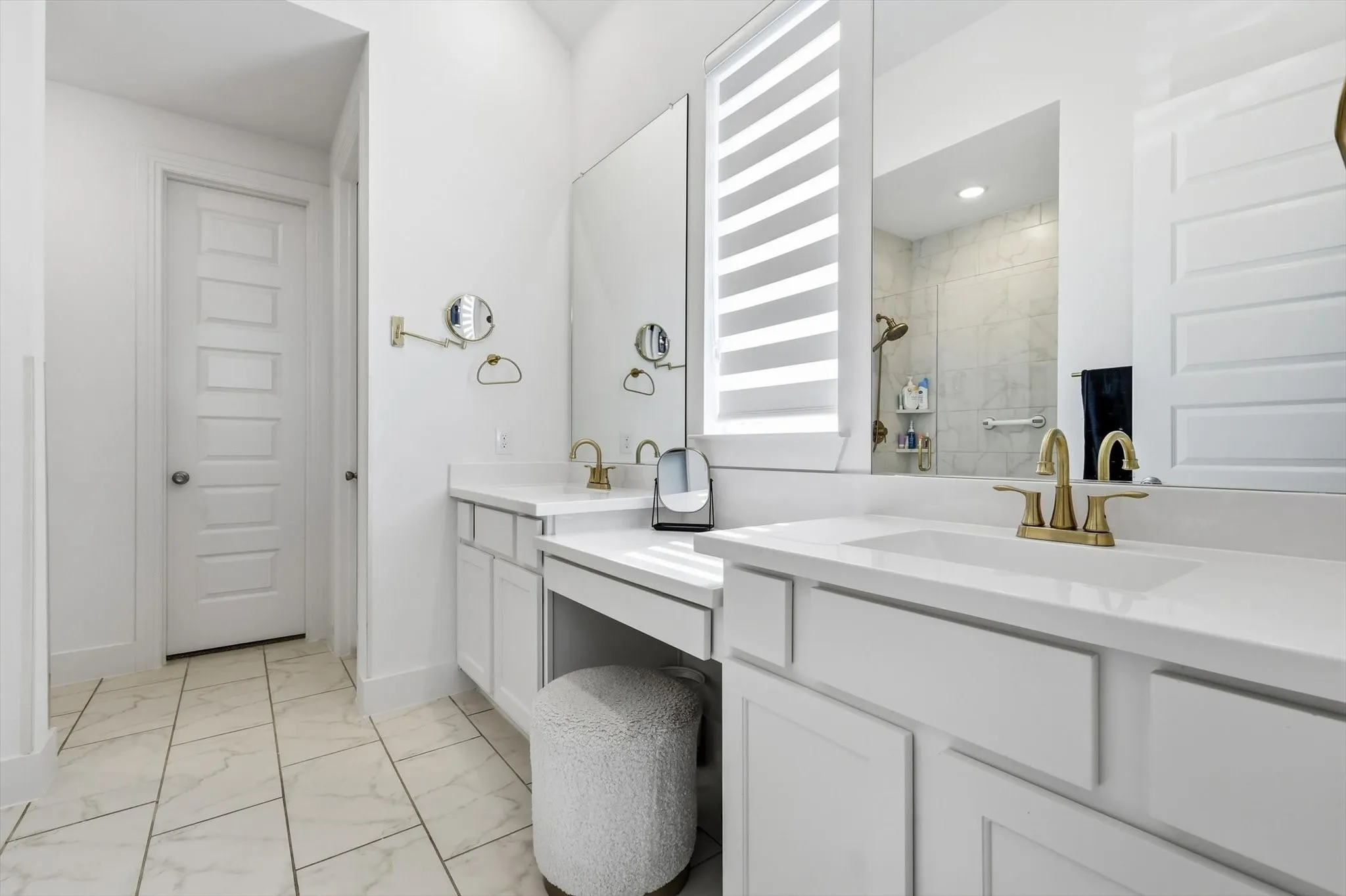 Dual vanity with white cabinetry, integrated sinks, and gold-finish fixtures