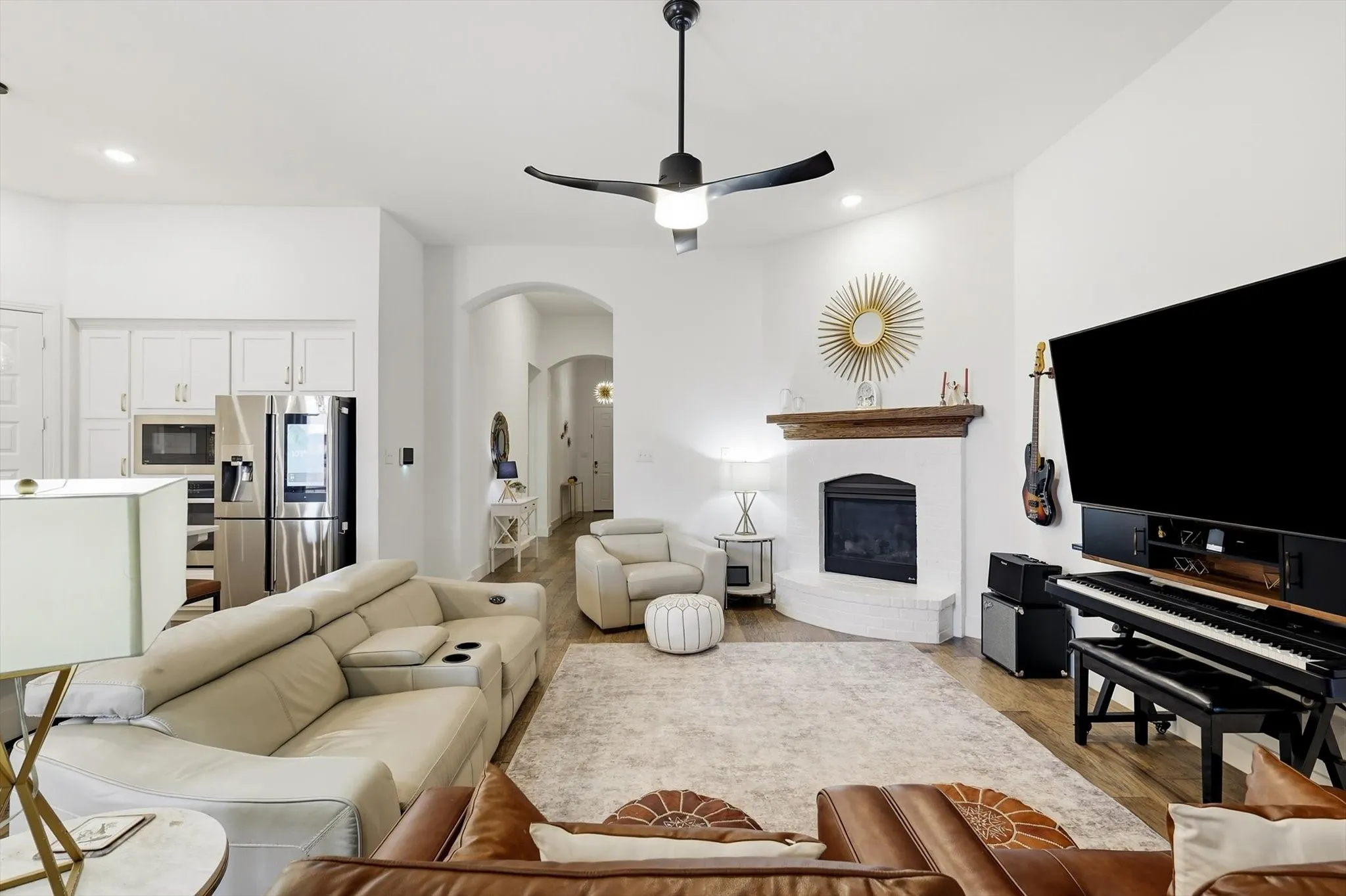 Spacious living area featuring a corner fireplace with a wood-finish mantel and a contemporary ceiling fan