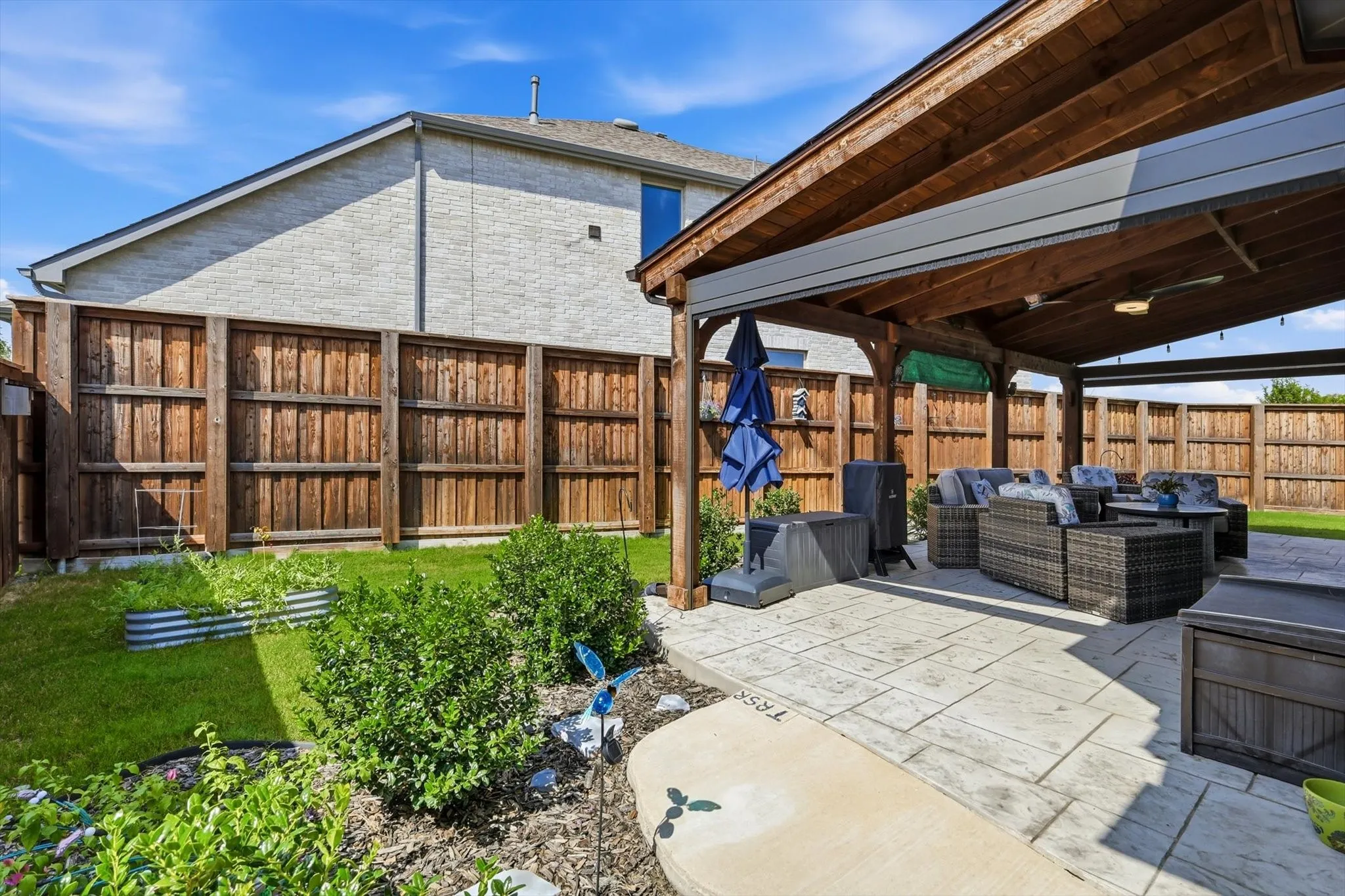Expansive covered patio featuring a wood-beam ceiling, stamped concrete flooring, and an integrated ceiling fan