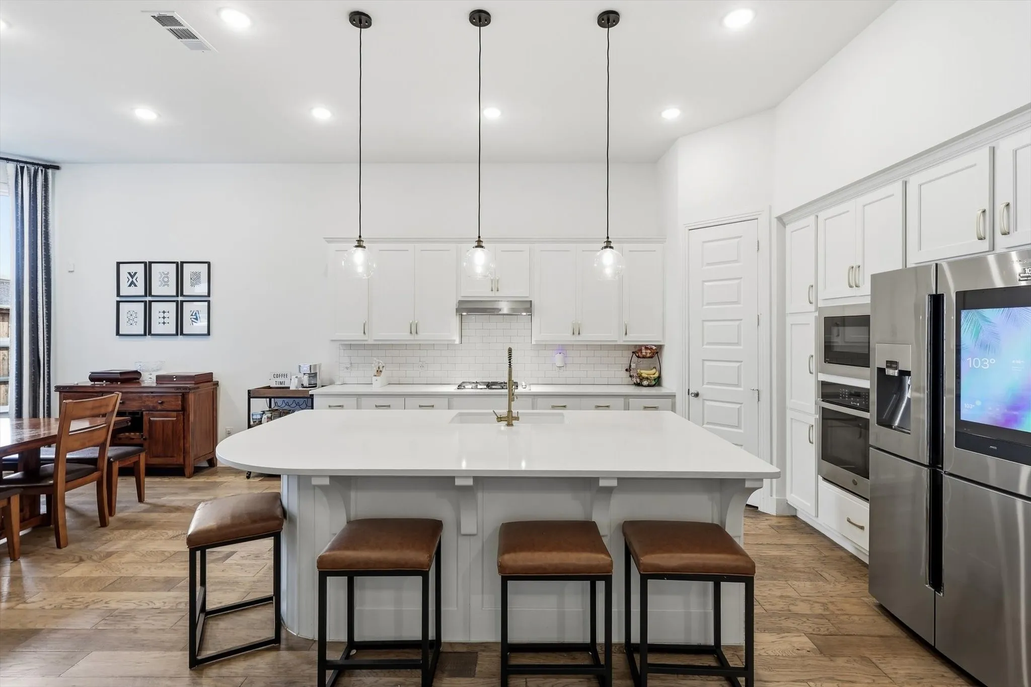 Gourmet kitchen featuring a large island with seating, white shaker cabinetry, stainless steel appliances, a subway tile backsplash, and recessed lighting
