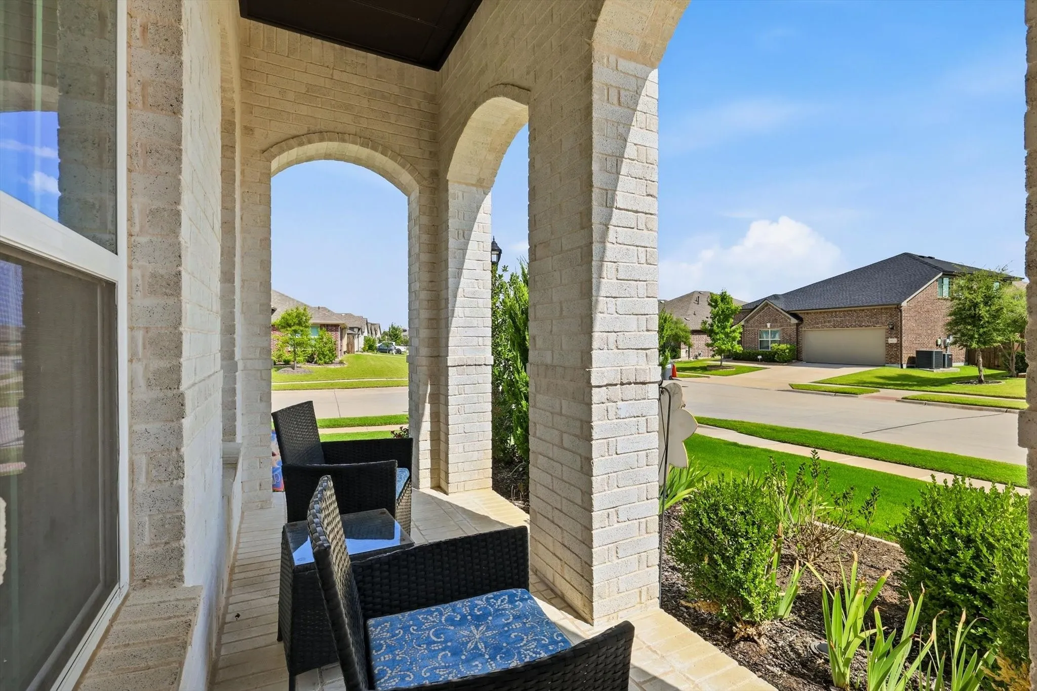 Covered porch featuring light brick construction and arched openings