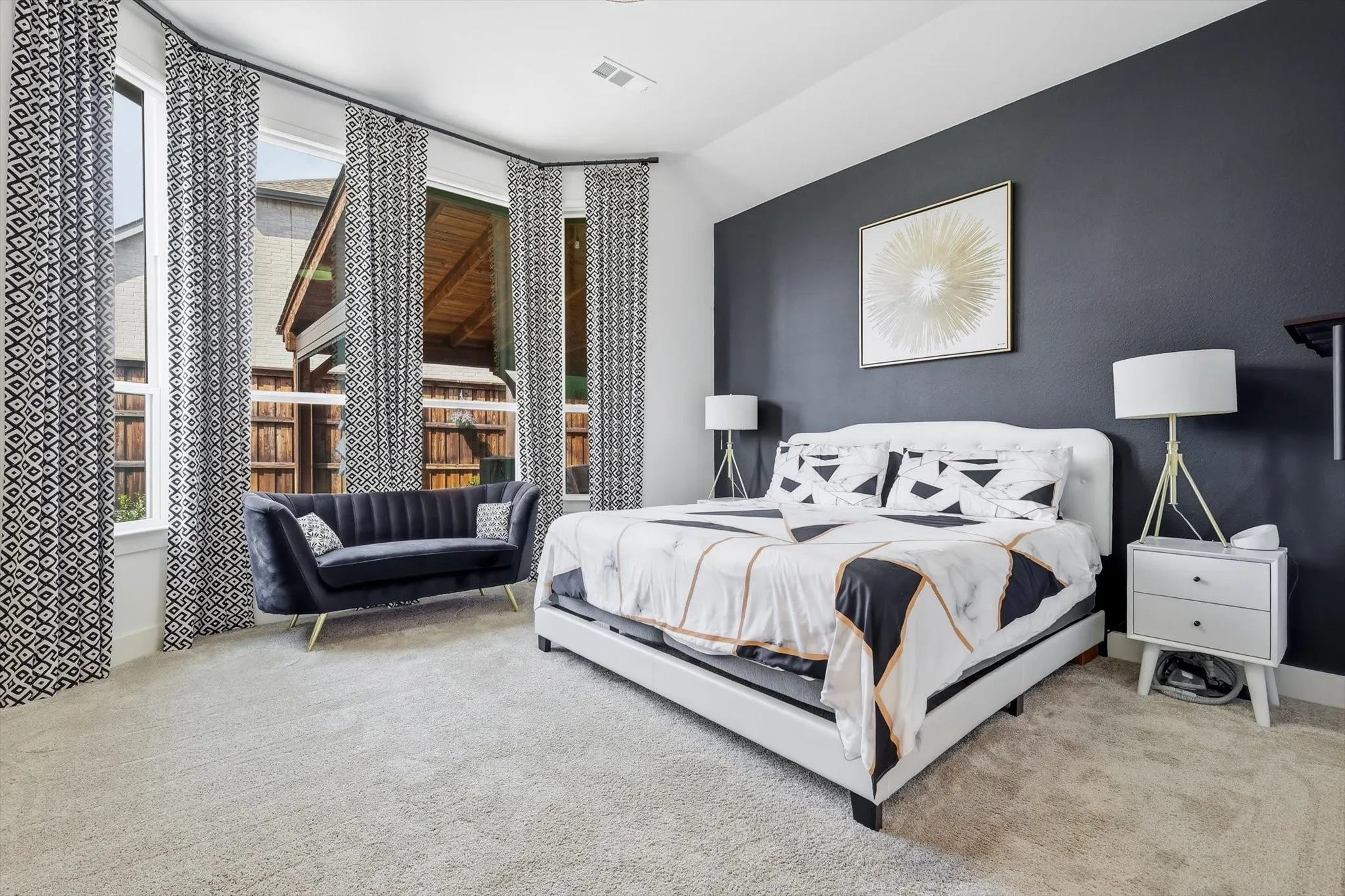 Expansive bay windows with patterned drapes, plush carpeting, and a dark accent wall