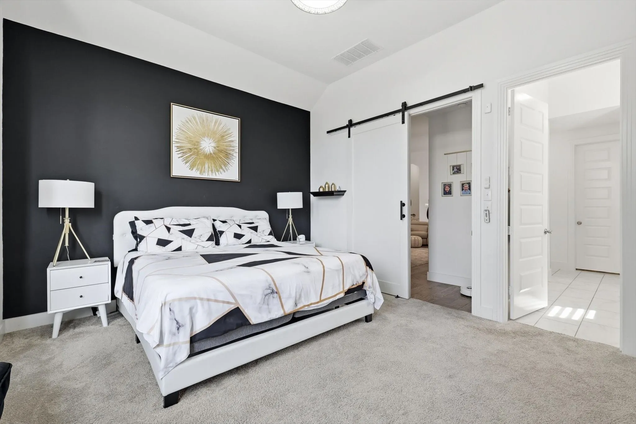 Room featuring a dark accent wall, vaulted ceiling, and light-toned carpeting