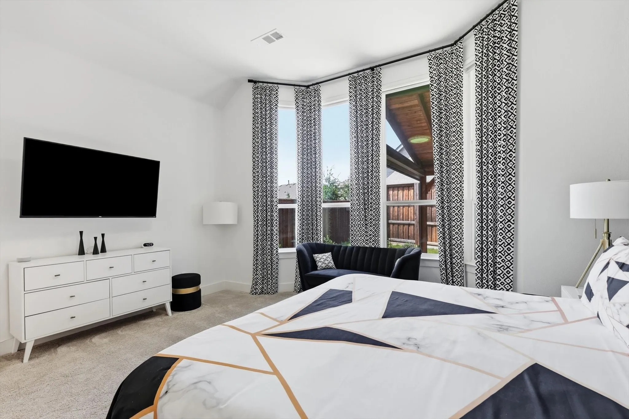 Bright room featuring a prominent bay window with three large panes, white walls, and light-colored carpeting