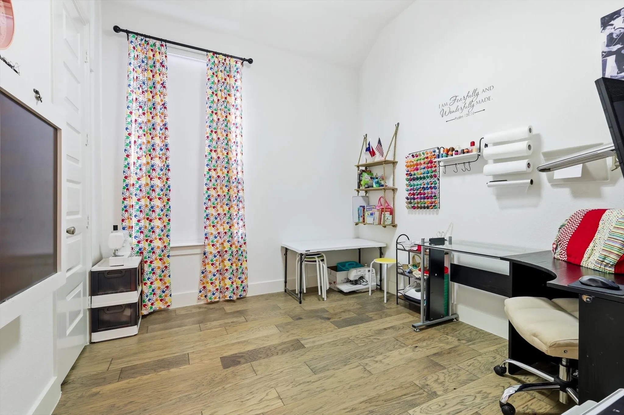Spacious room featuring light wood-finish flooring, white walls, and a vaulted ceiling