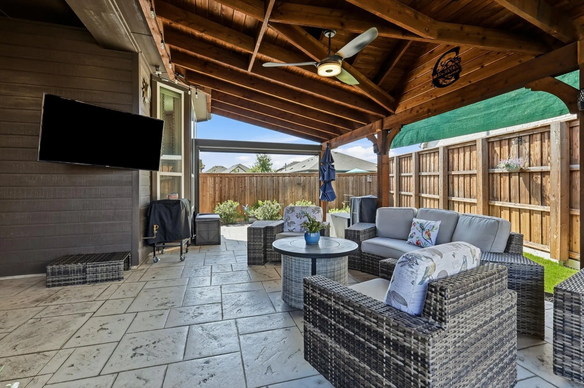 Expansive covered patio featuring a wood-beam ceiling, stamped concrete flooring, and a ceiling fan