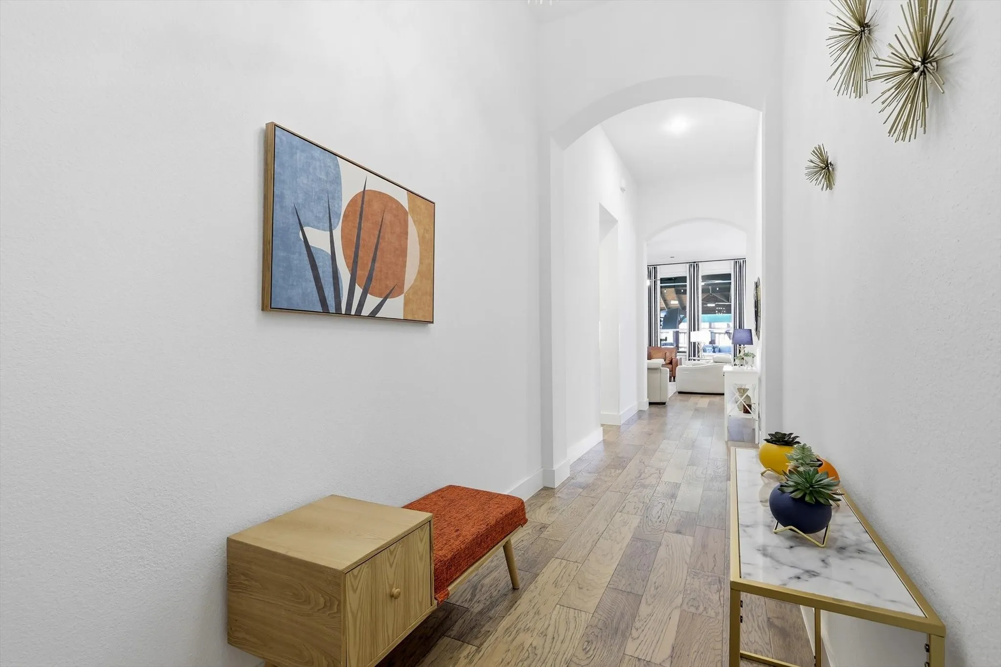 Hallway featuring wood-finish flooring, white walls, and an arched doorway