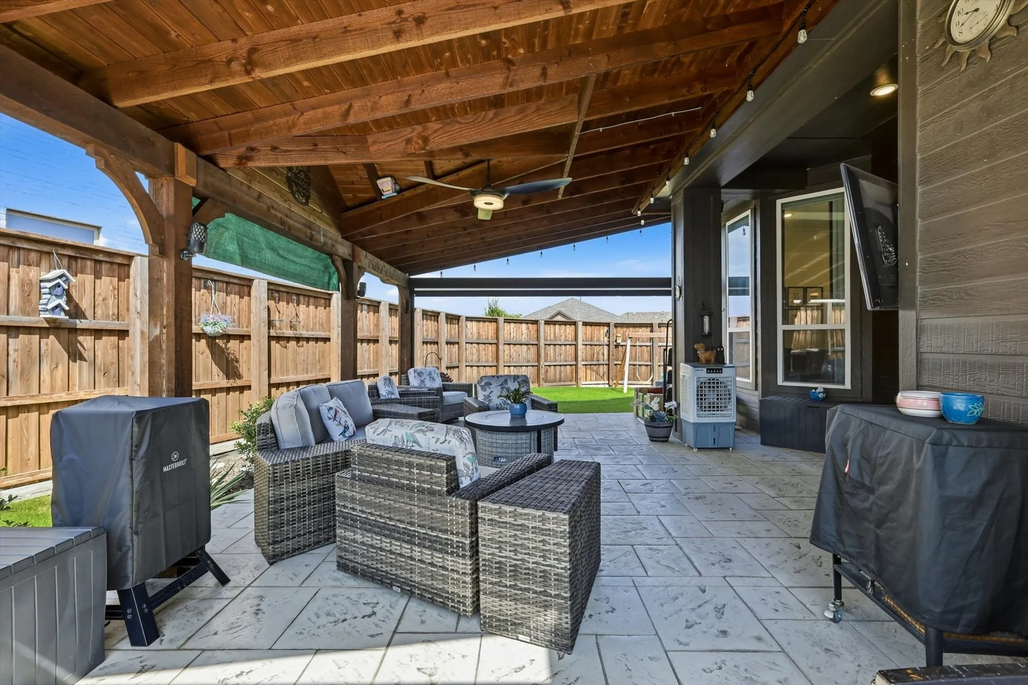 Covered patio with a wood-finish ceiling, exposed beams, and a ceiling fan