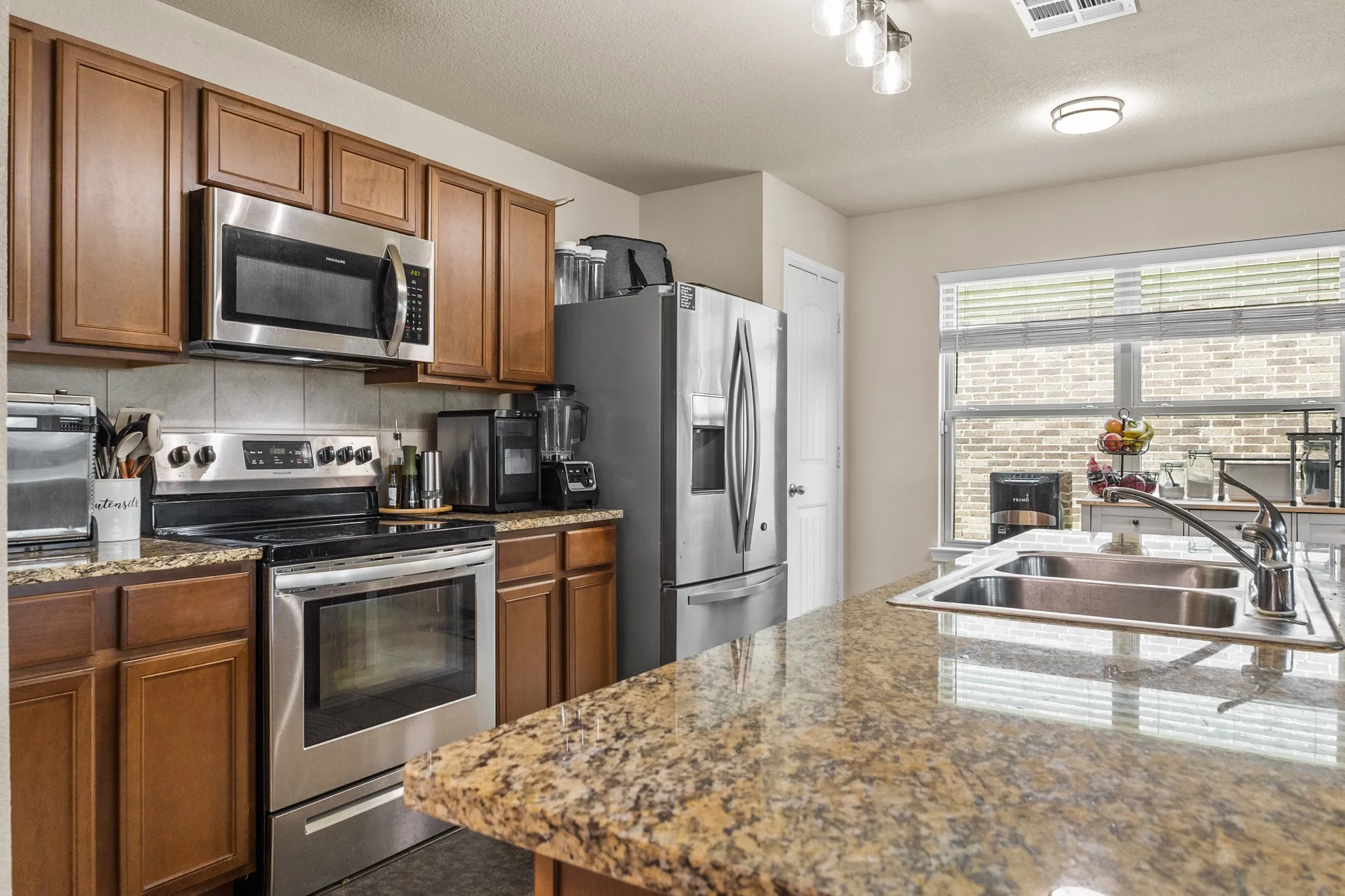 Kitchen featuring granite countertops, wood cabinetry, and stainless steel appliances including a built-in microwave and range