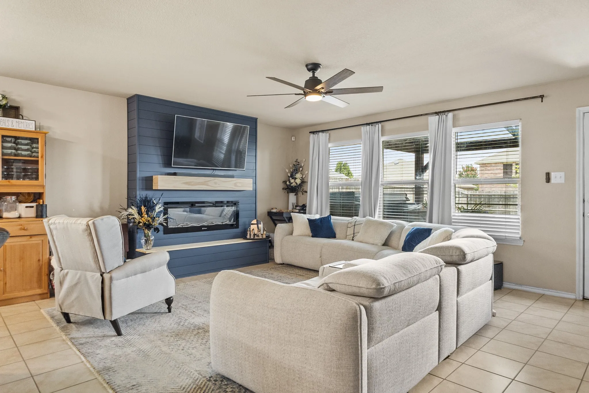 Living room featuring a modern electric fireplace with a shiplap surround, wood mantel, and integrated media space