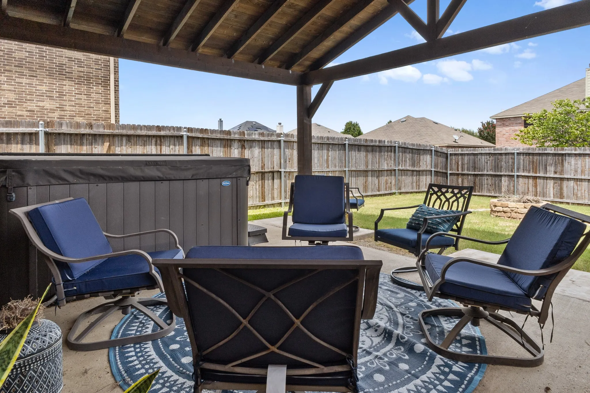 Covered patio featuring a wood-beam ceiling, concrete flooring, and an attached hot tub