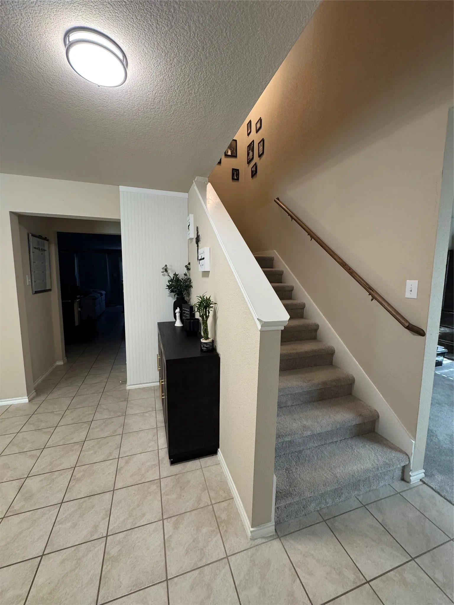 Foyer featuring diagonal tile flooring, a staircase with carpeted treads and a wood handrail, and a contemporary ceiling light fixture