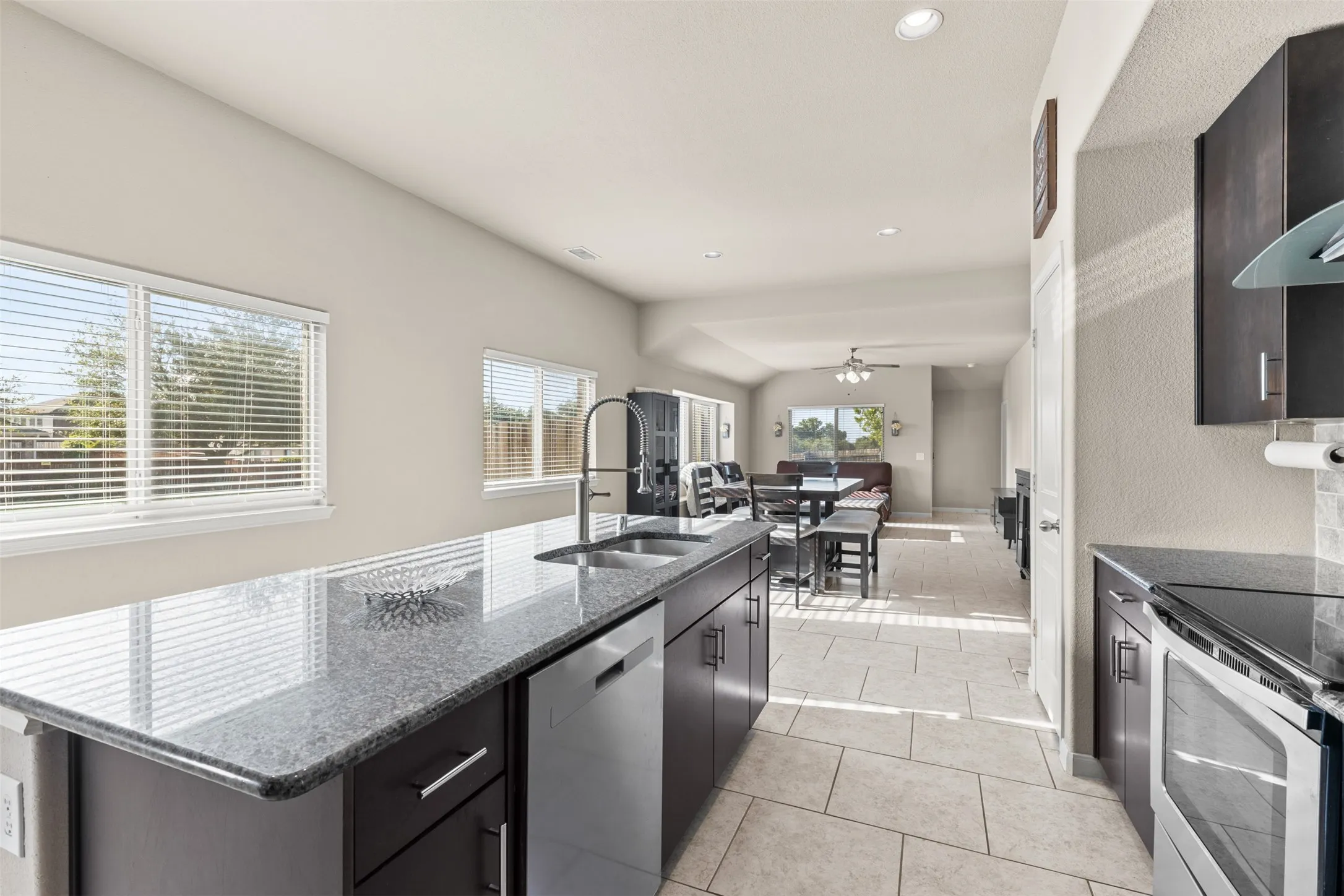 Kitchen features dark cabinetry, granite countertops and stainless appliances