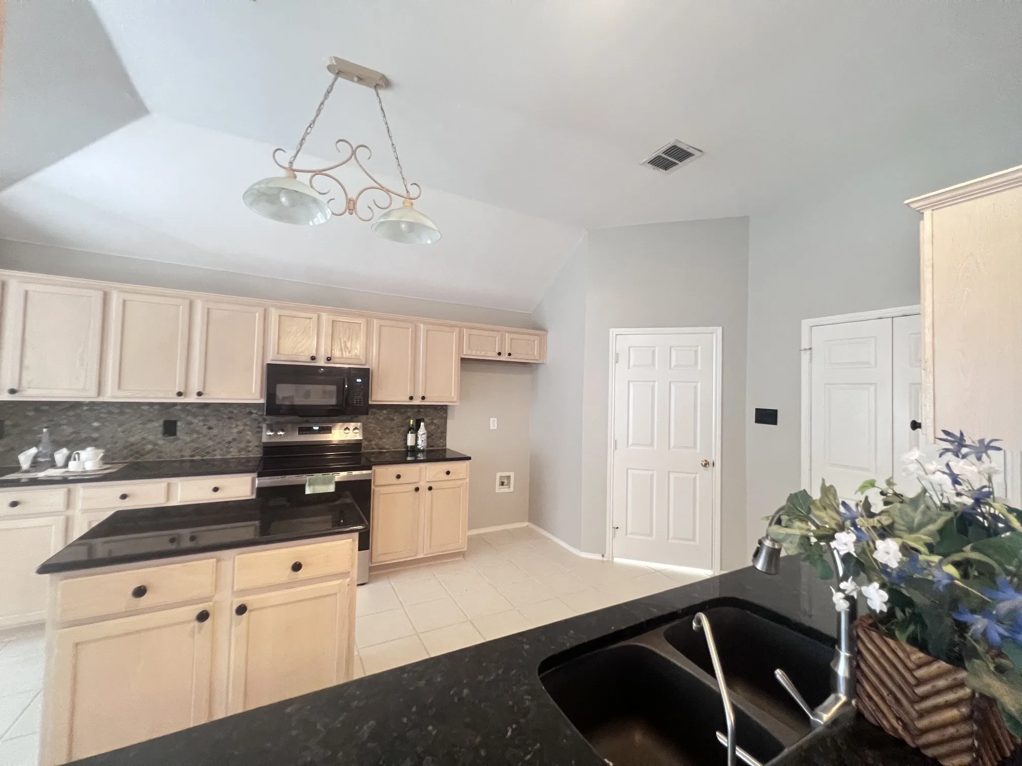 Kitchen featuring light-toned cabinetry, dark countertops, and a central island