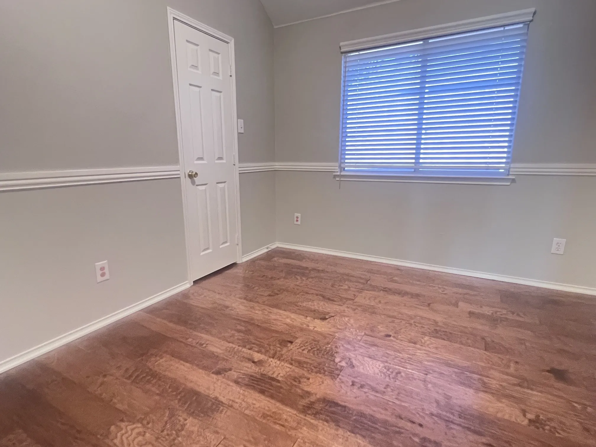 Room featuring wood-finish flooring, neutral wall tones, and white baseboards