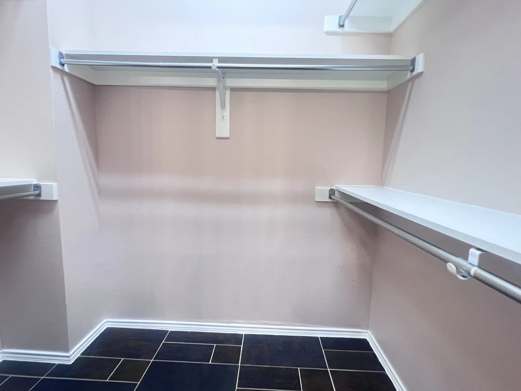 Built-in closet system featuring multiple white shelves and chrome hanging rods