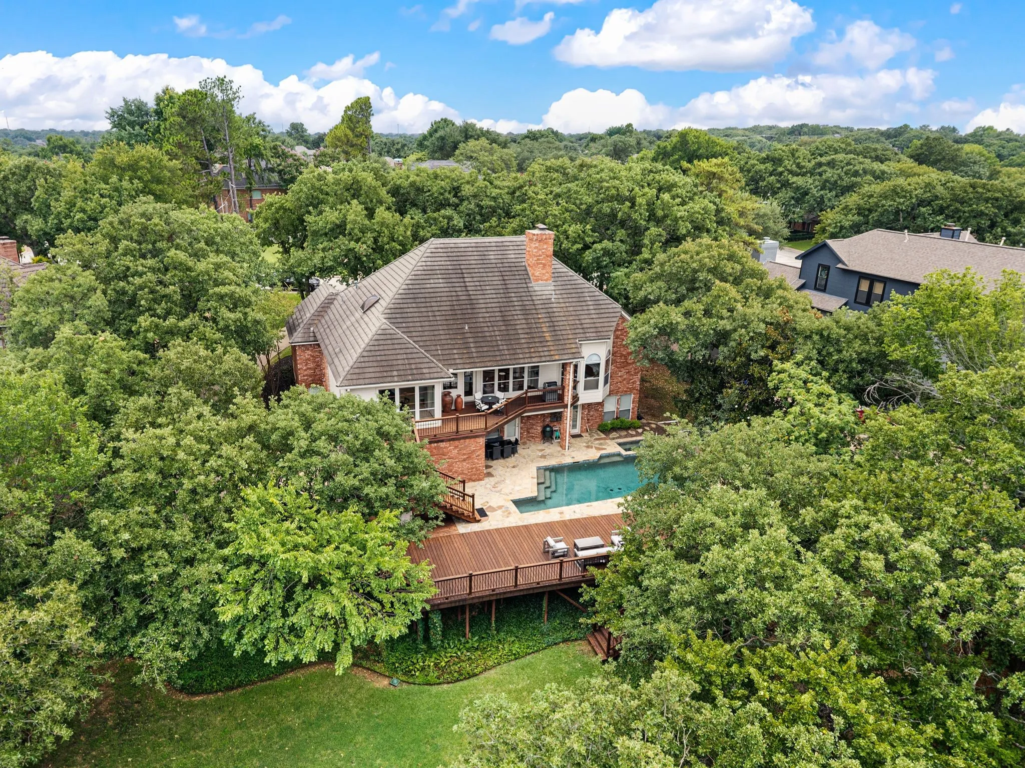 Brick exterior residence with a multi-level wood deck, an in-ground swimming pool, and a private yard
