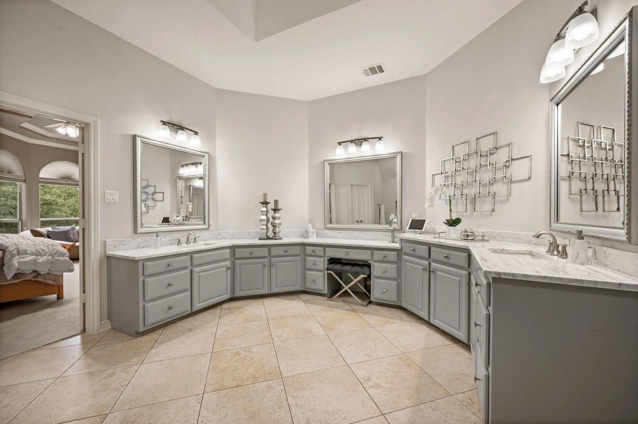 Spacious bathroom featuring light gray cabinetry, white marble countertops, and dual vanity areas with undermount sinks