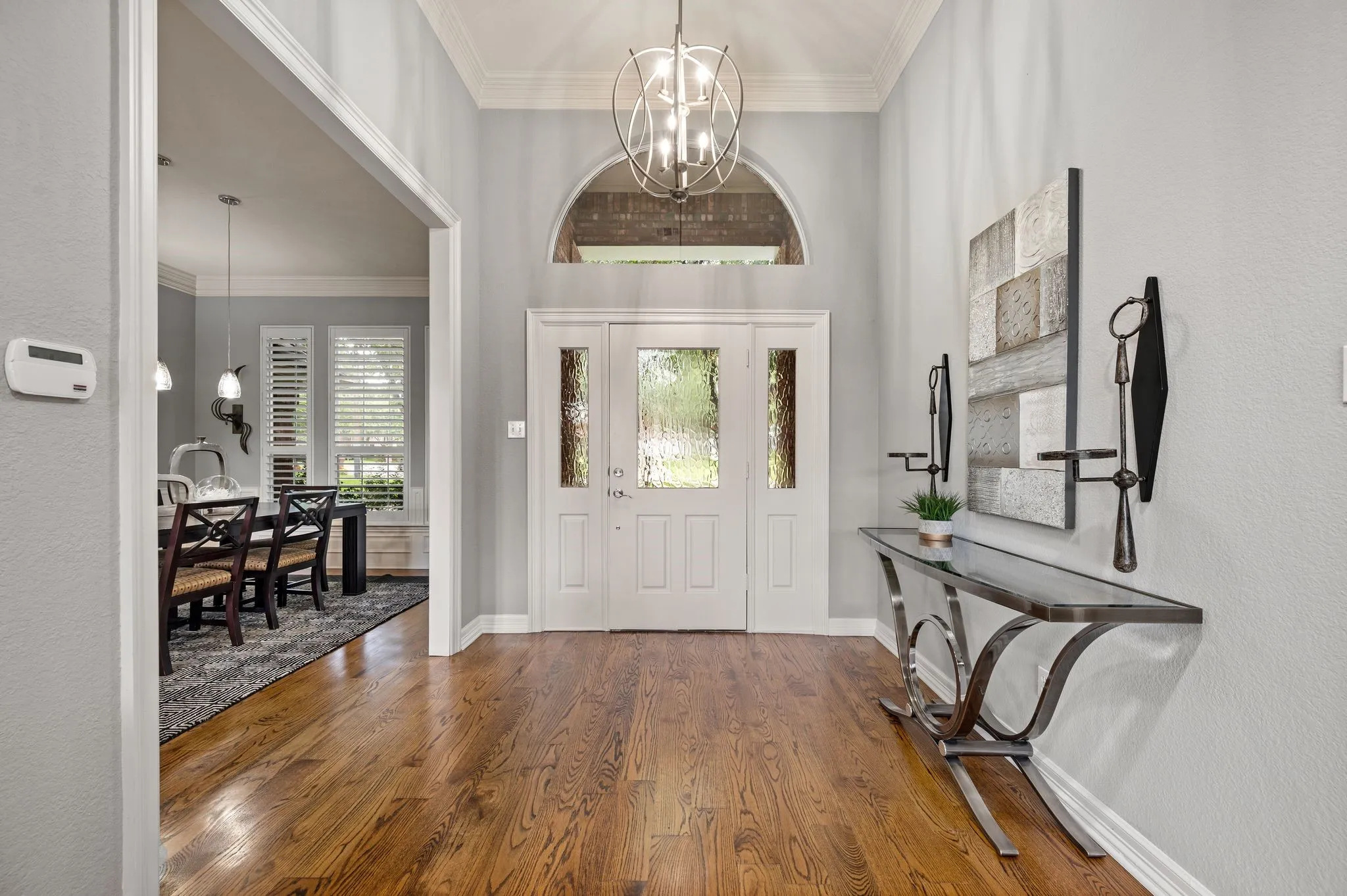 Grand entryway featuring rich wood-finish flooring, a double front door with decorative glass inserts, and a transom window
