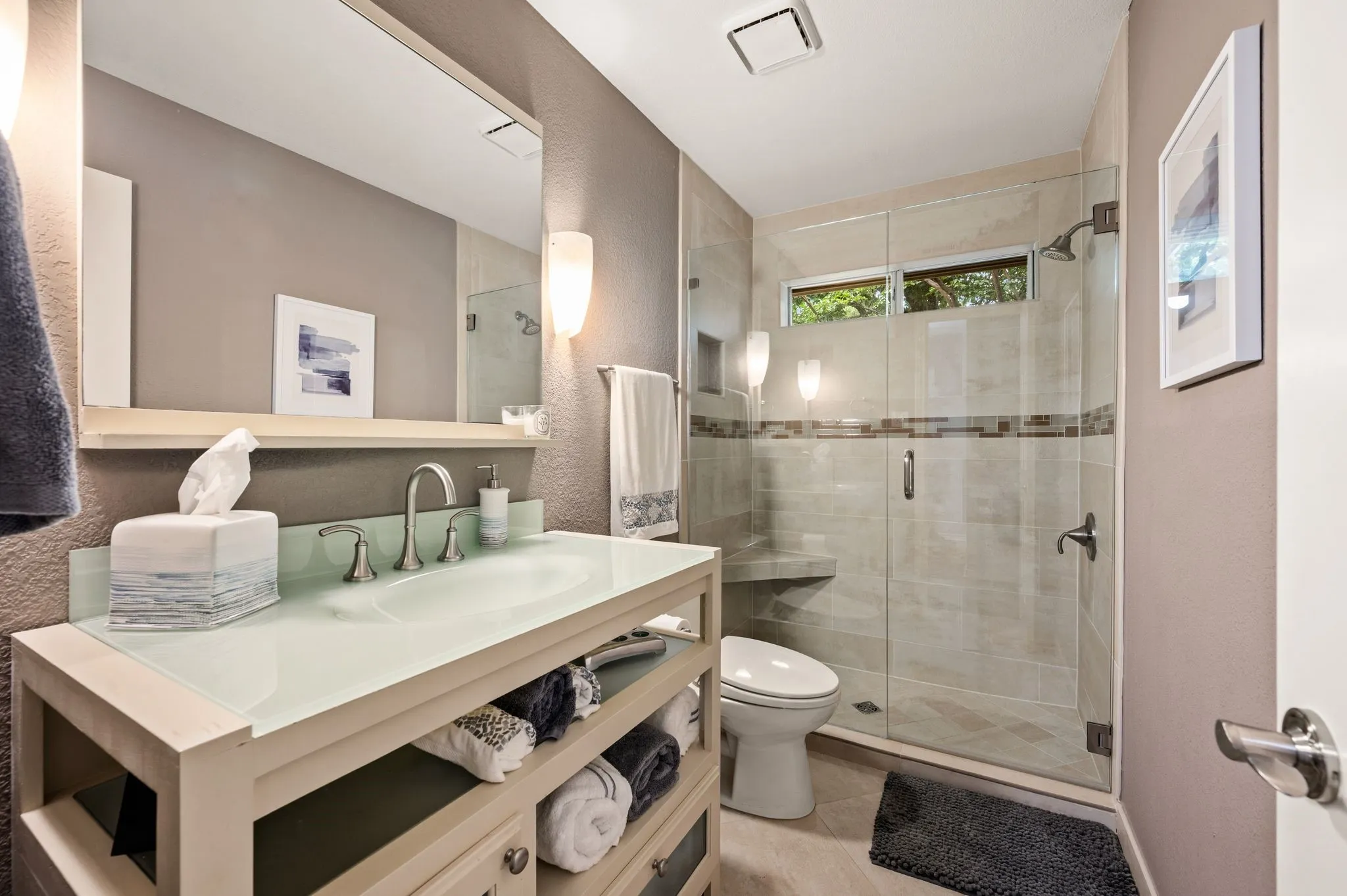 Contemporary bathroom featuring a spacious glass-enclosed shower, a built-in shower bench, and transom windows