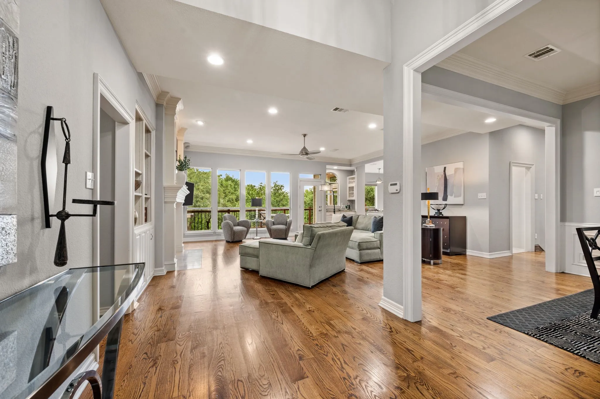 Spacious open-concept living area featuring rich wood-finish flooring, recessed lighting, and expansive windows