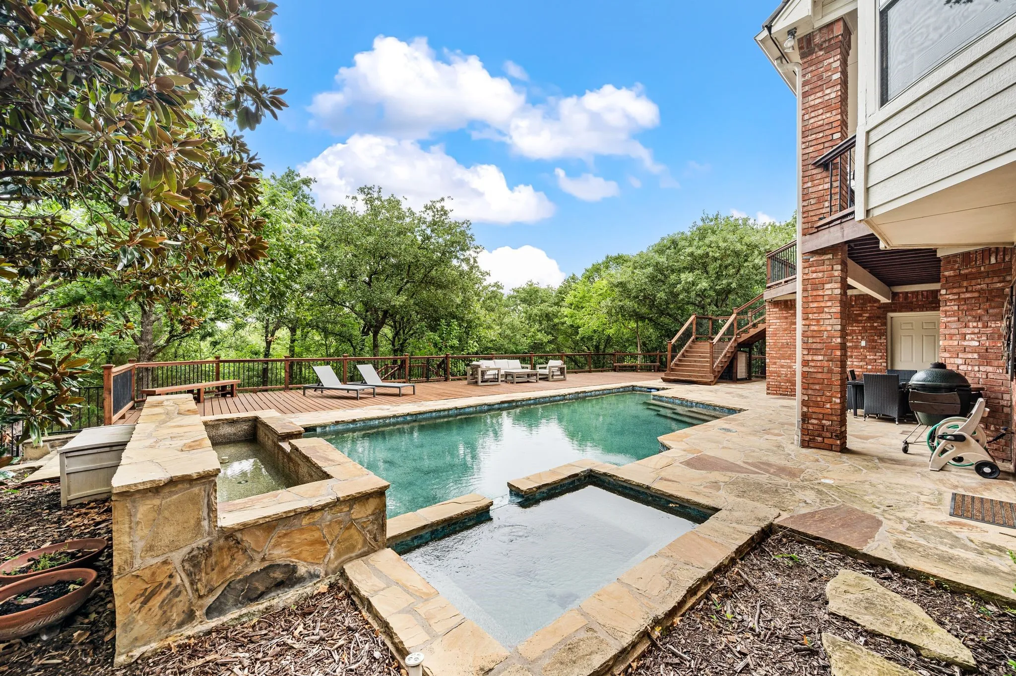 Outdoor swimming pool with integrated spa and natural stone coping